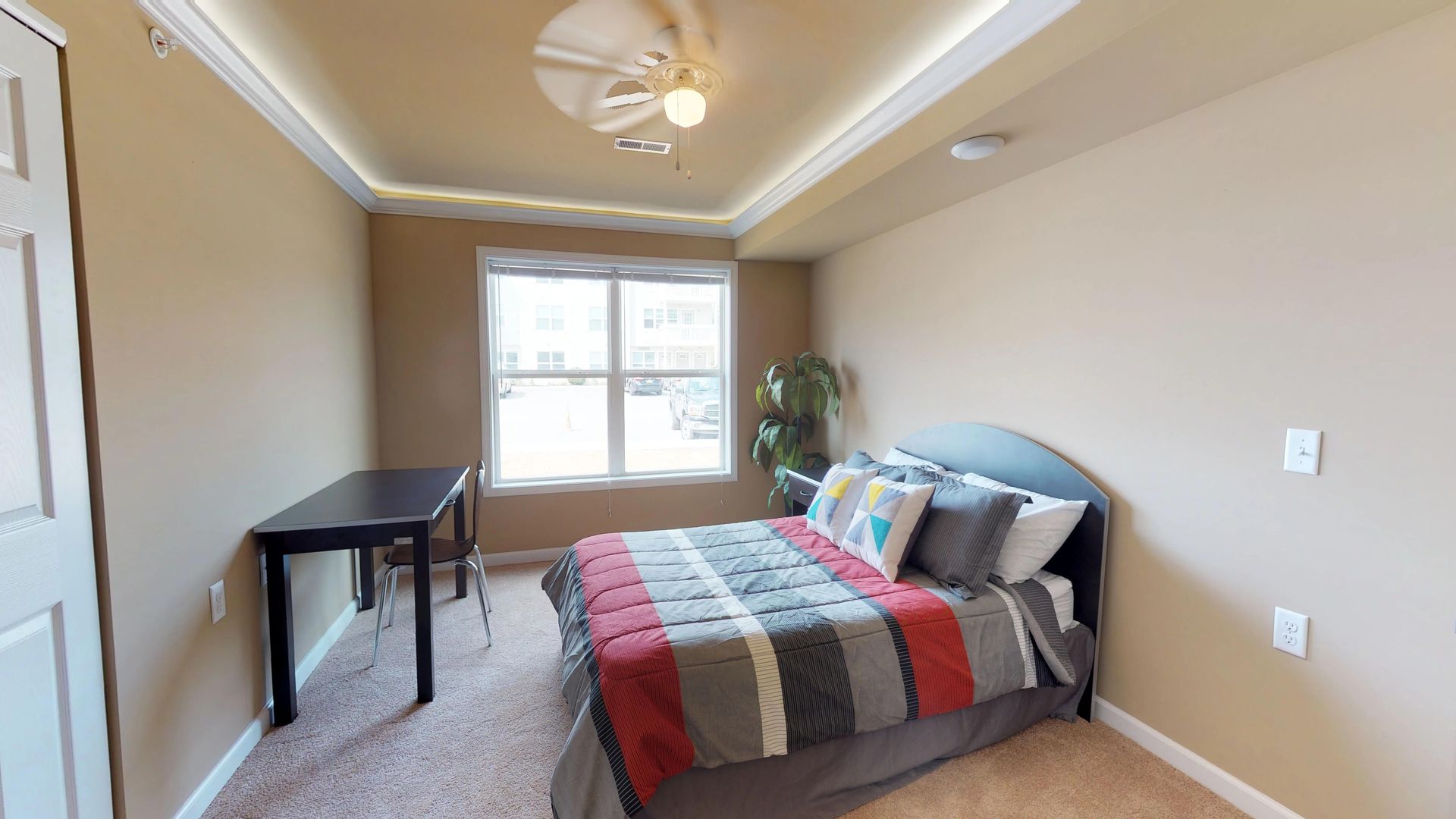 A bedroom with a bed , desk , and ceiling fan.