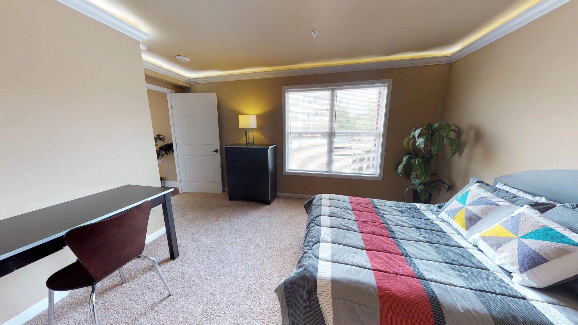 A bedroom with a bed , desk , chair and window.