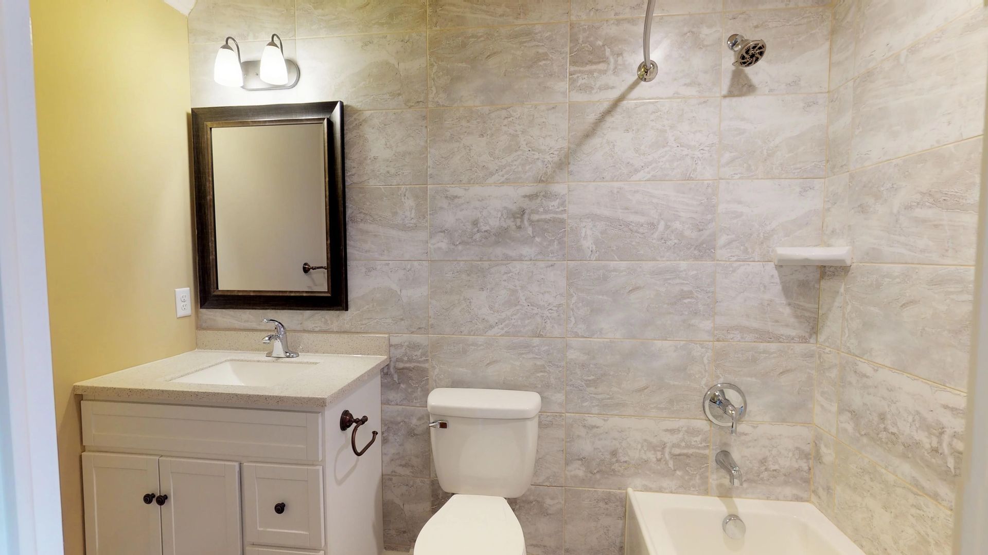 A bathroom with a toilet , sink , mirror and bathtub.