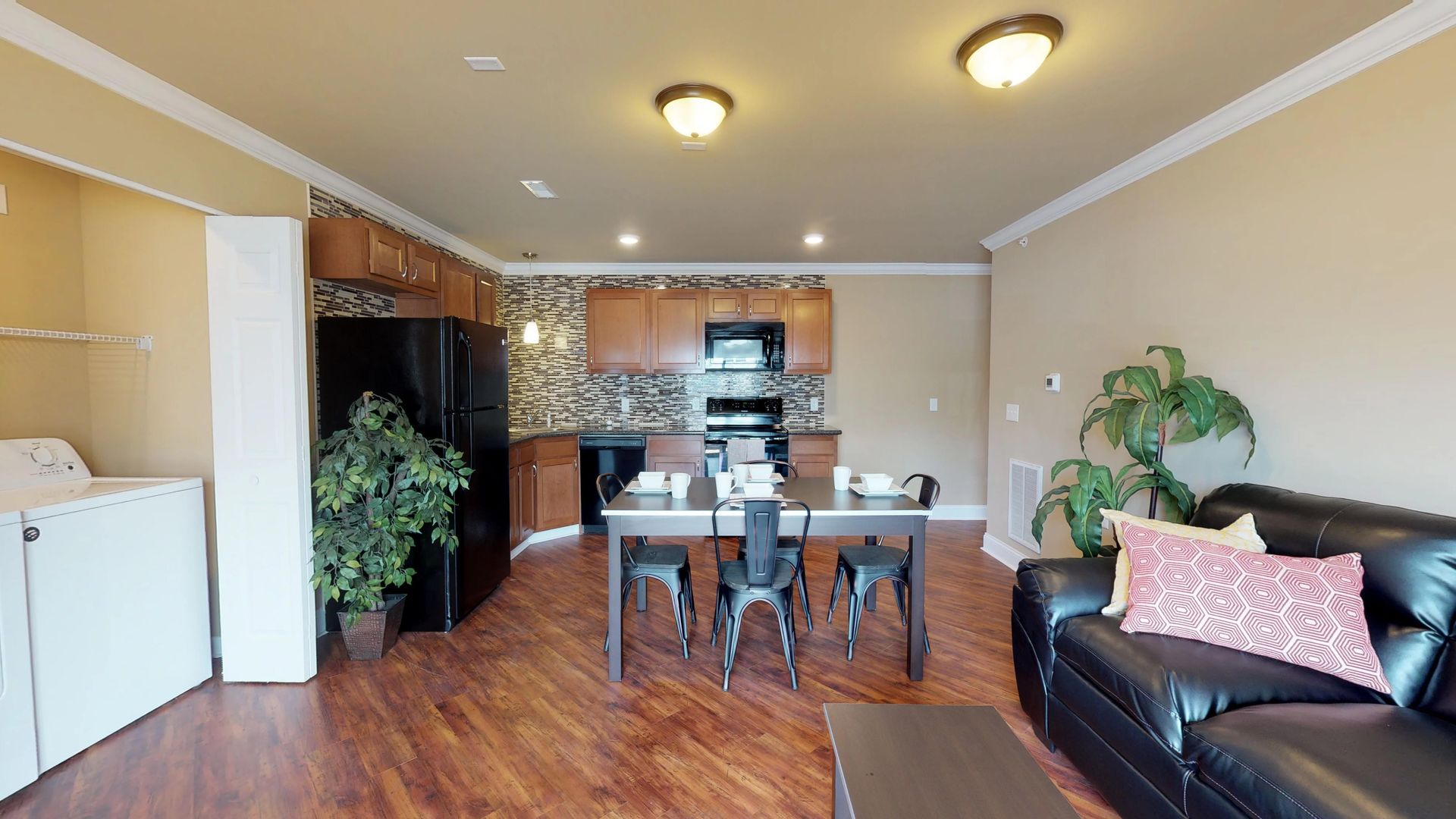 A living room with a couch , table , chairs and a refrigerator.