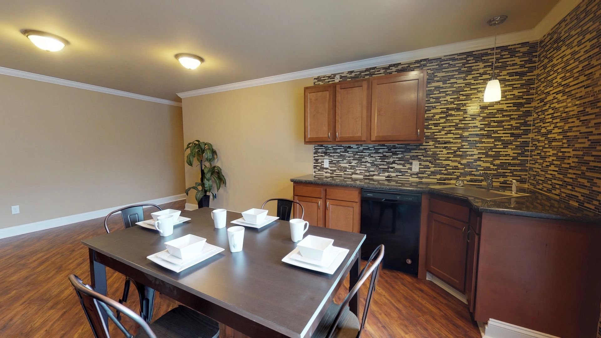 A dining room table with plates and cups on it in a kitchen.