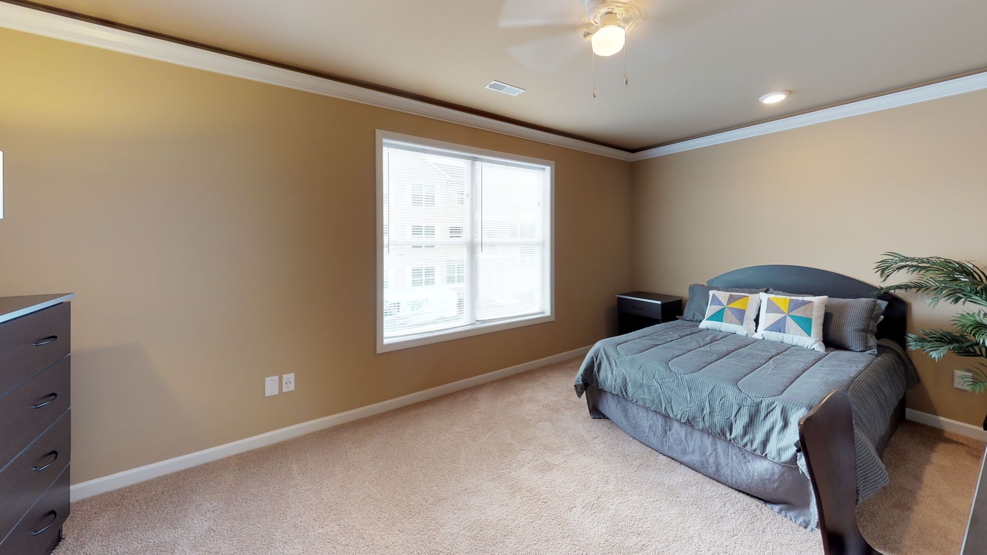 A bedroom with a bed , dresser , and two windows.