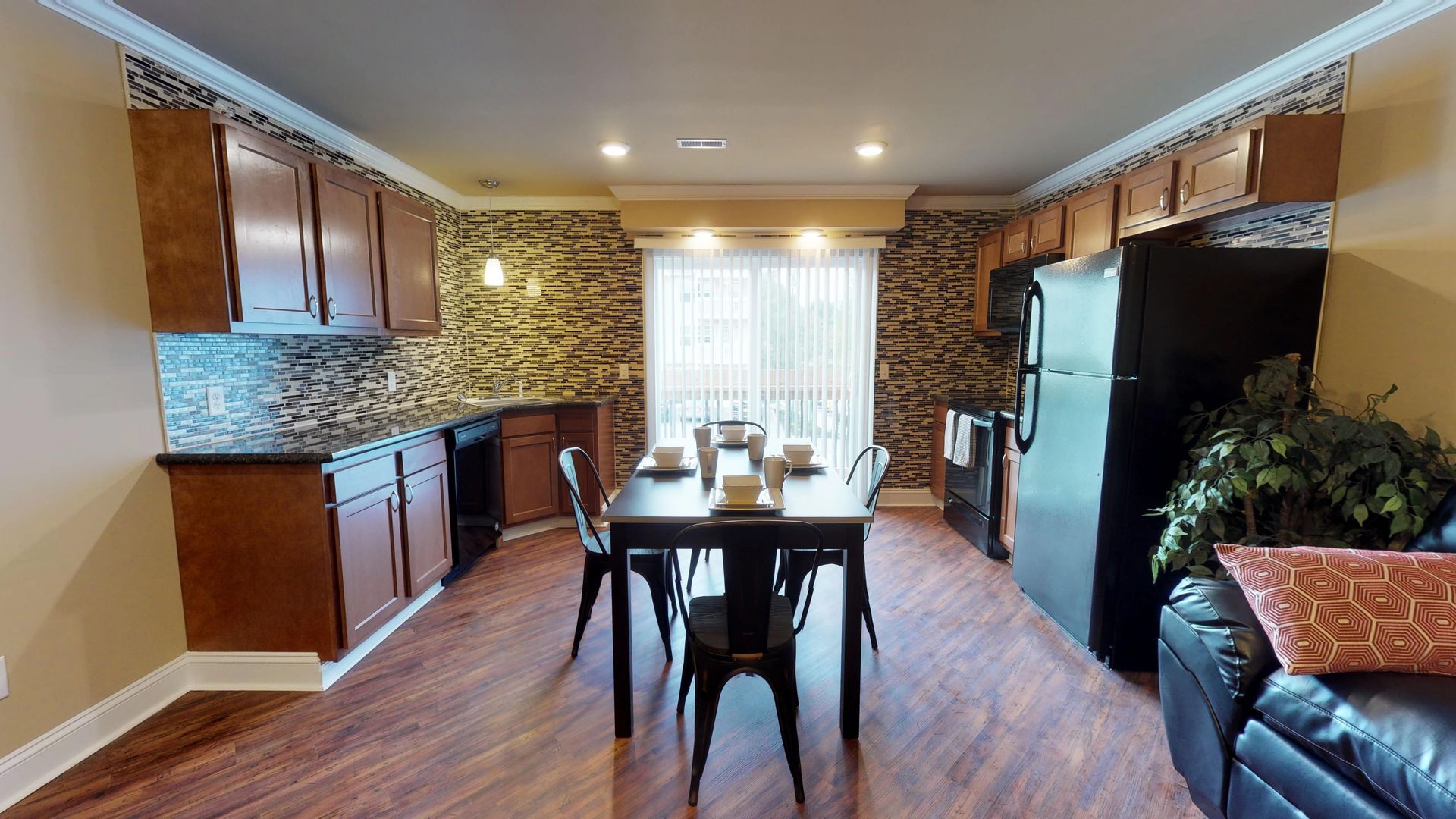 A living room with a dining table and chairs and a kitchen.