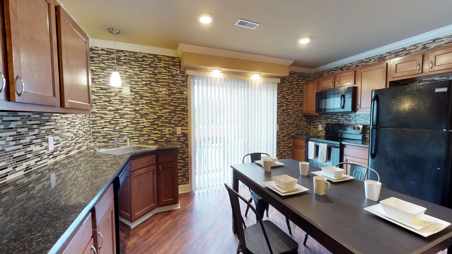 A kitchen with a large table and a black refrigerator