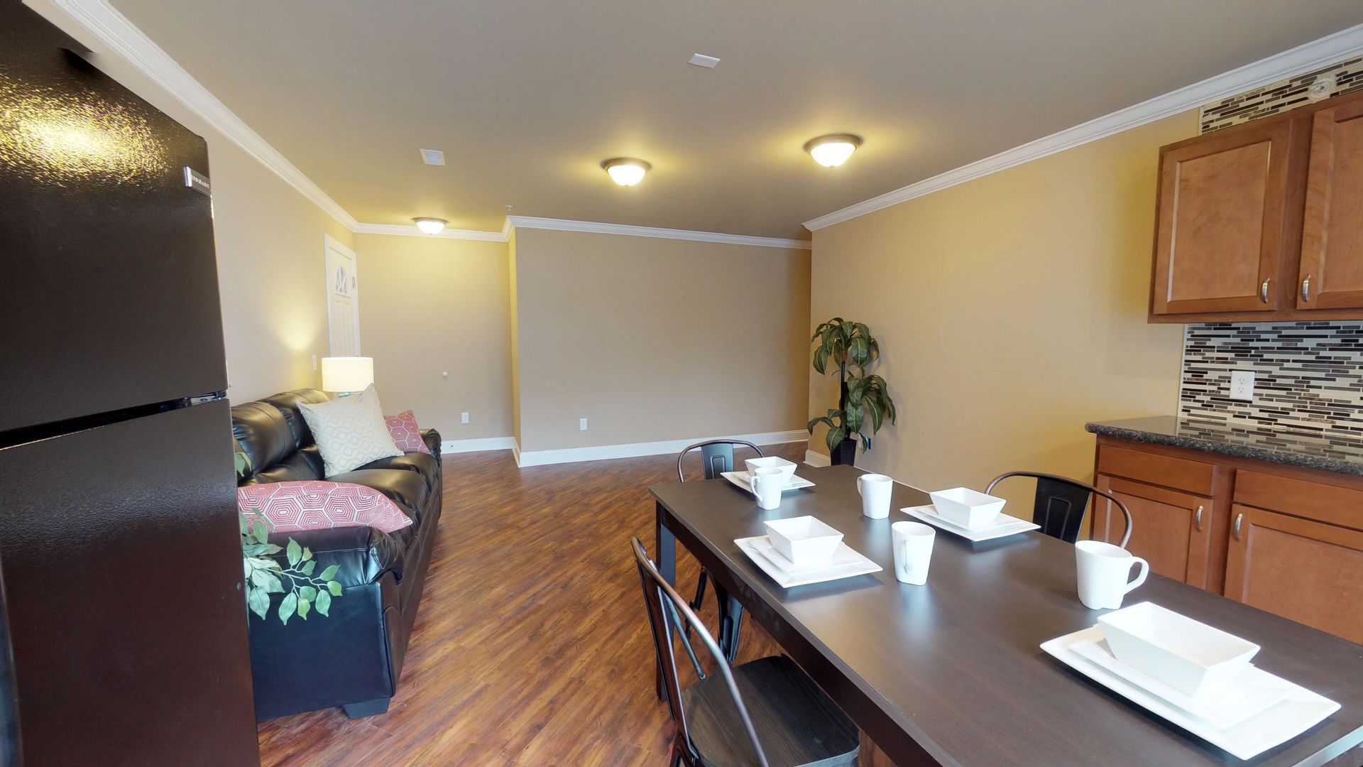 A living room with a dining table and a black refrigerator