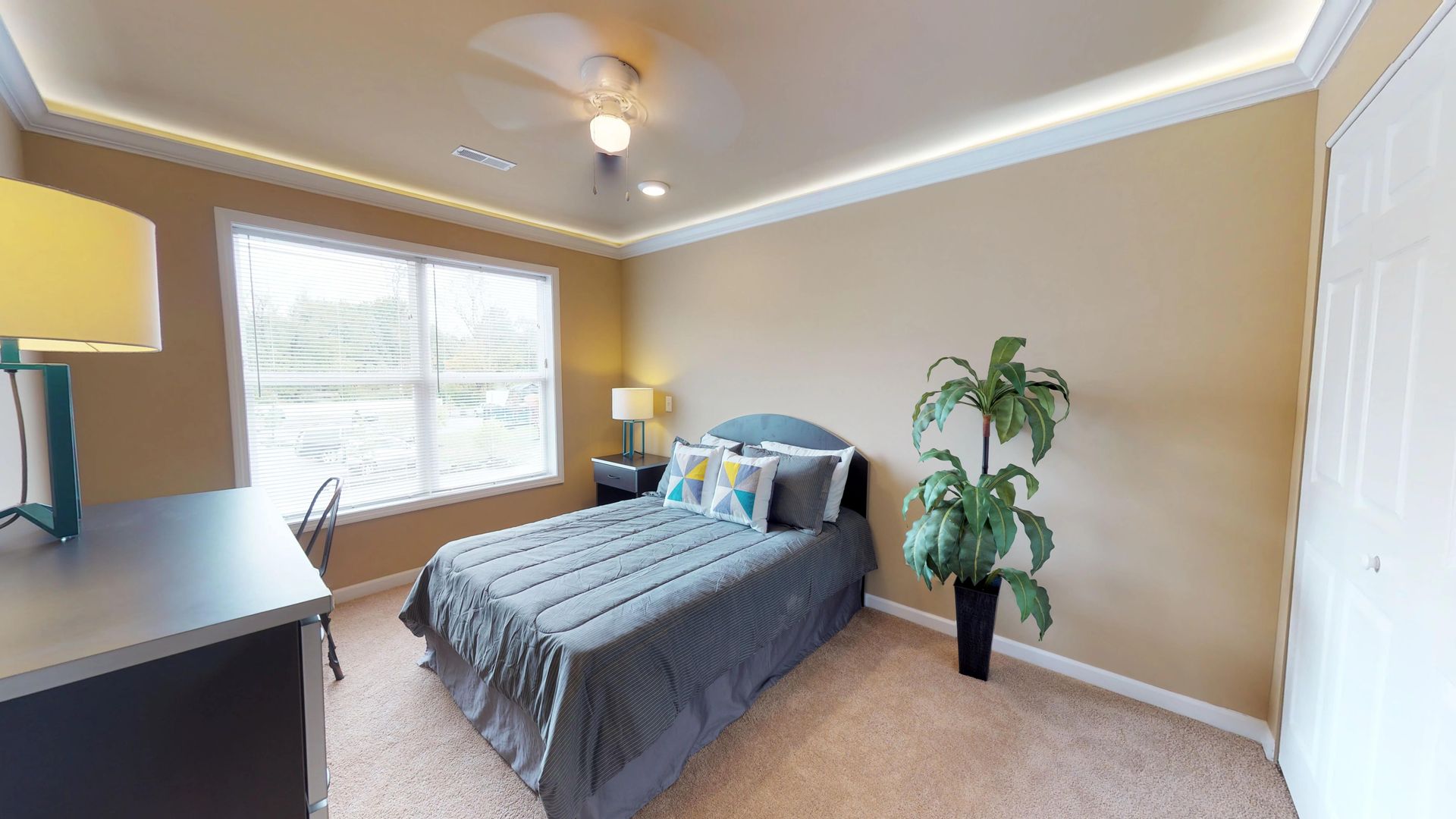 A bedroom with a bed , dresser , lamp , and window.
