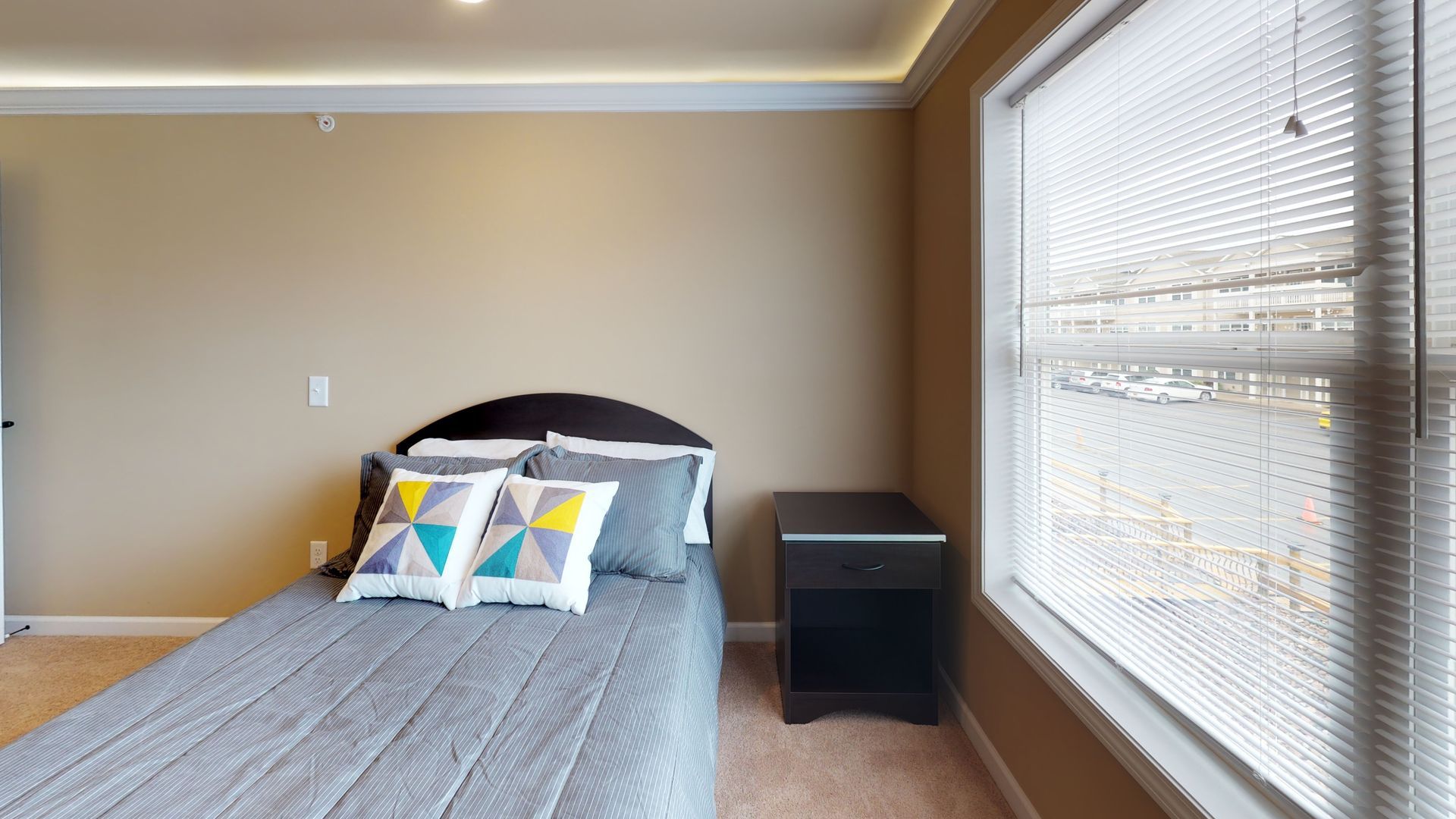 A bedroom with a bed , nightstand , and window with blinds.