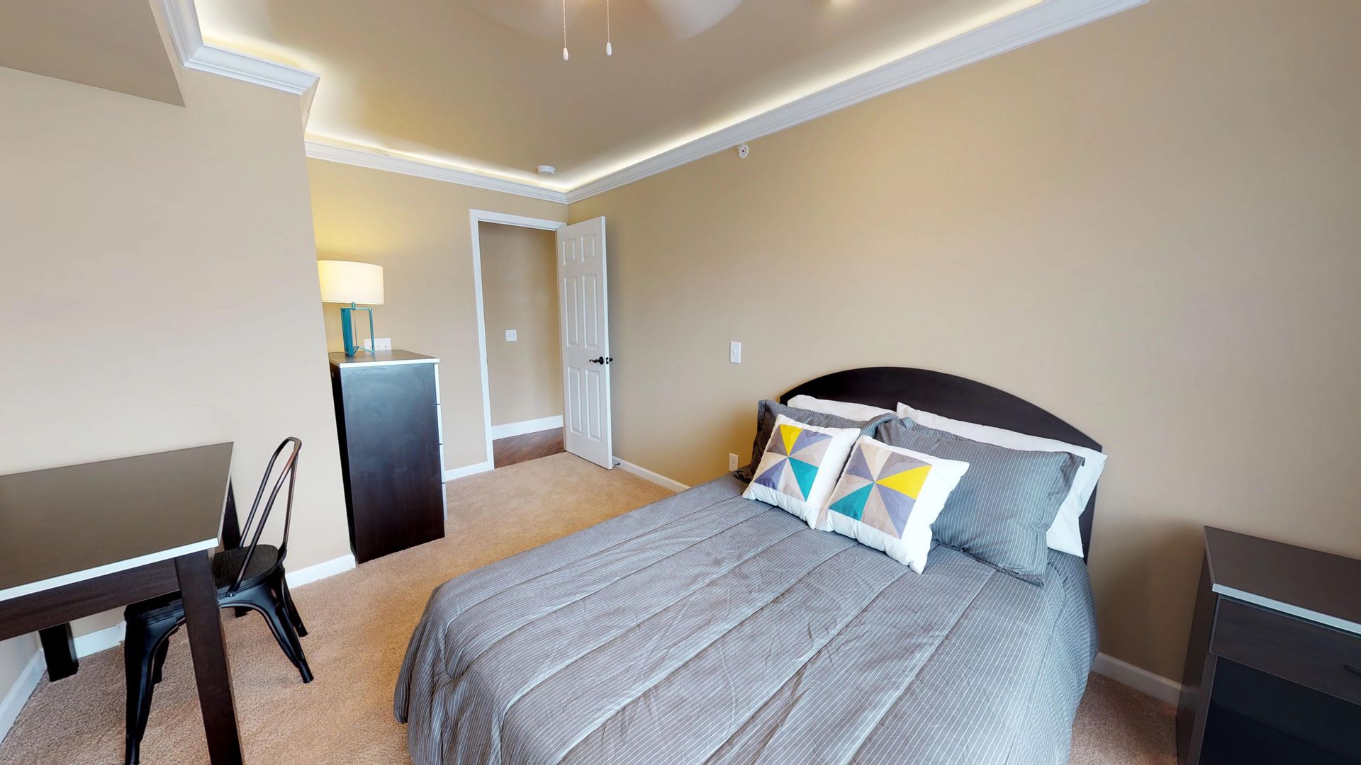 A bedroom with a bed , desk and chairs.