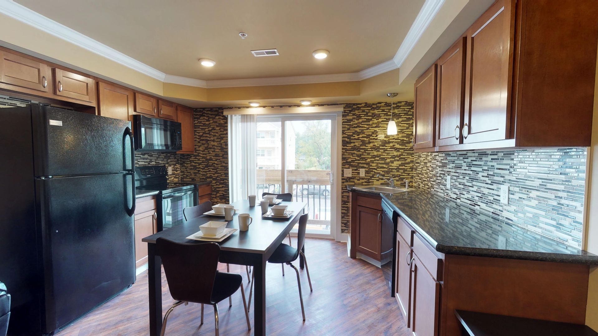 A kitchen with a table and chairs and a black refrigerator