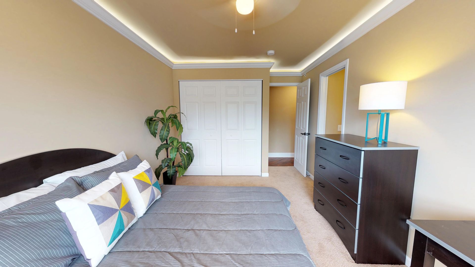 A bedroom with a bed , dresser and lamp.