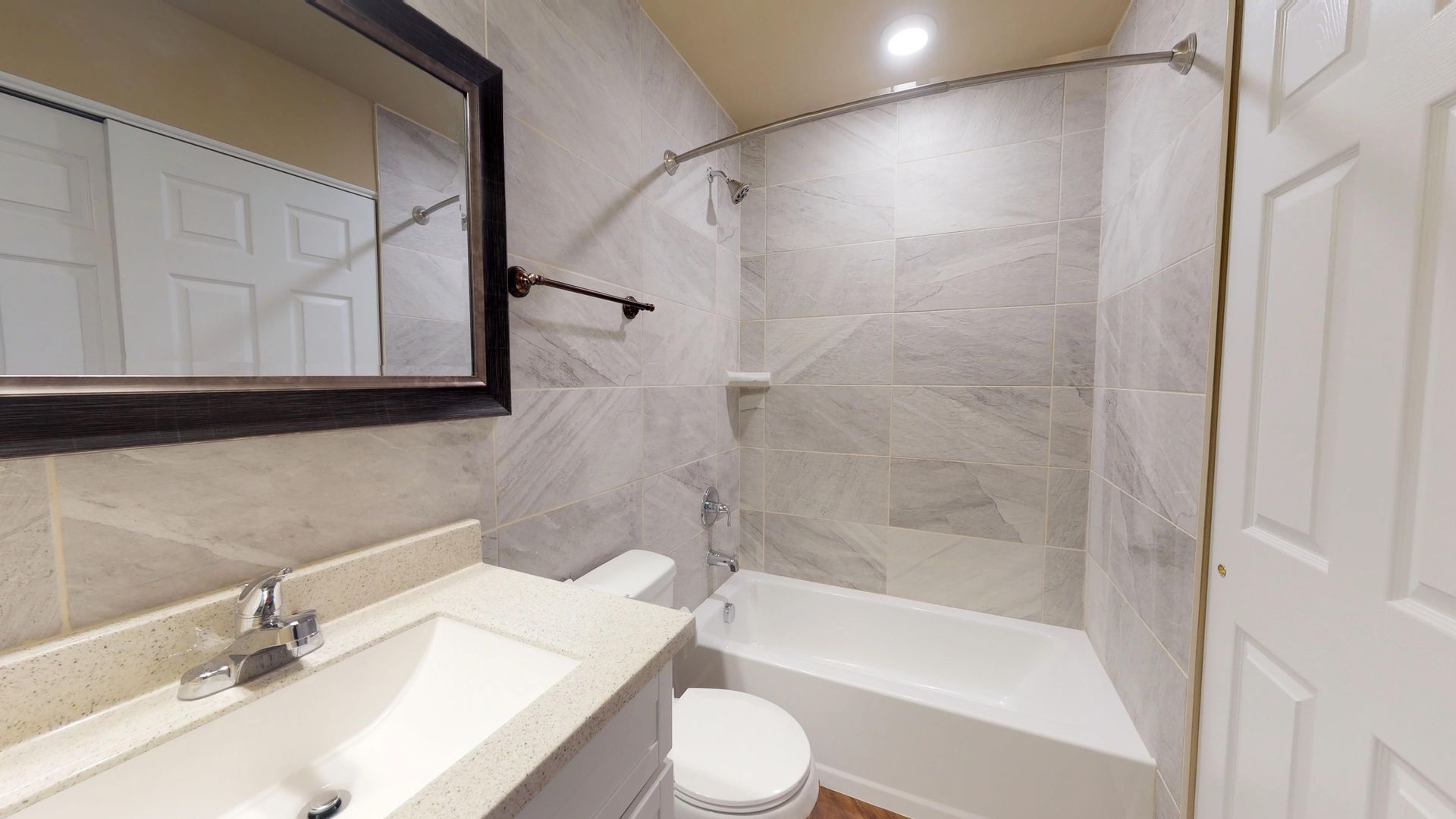 A bathroom with a sink , toilet , tub and mirror.