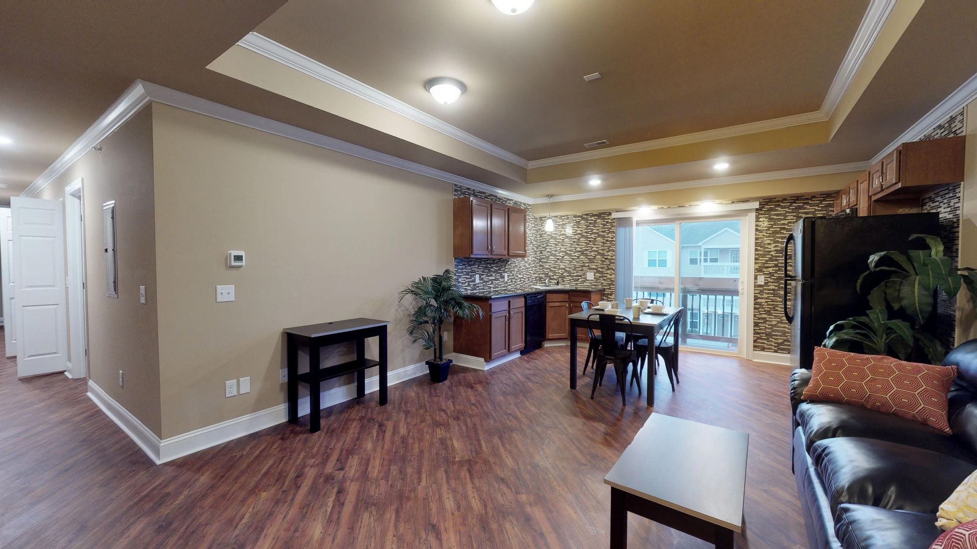 A living room with hardwood floors , a couch , table and chairs.
