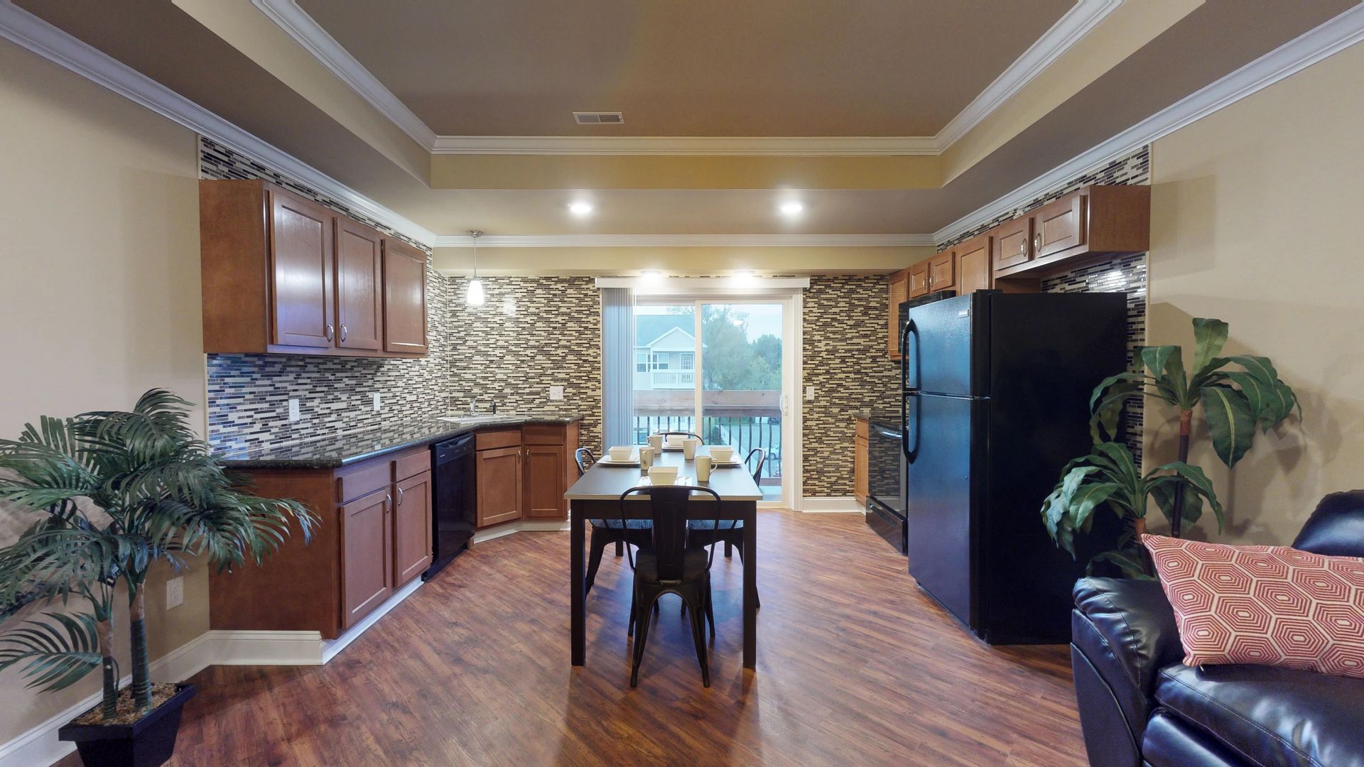 A living room with a dining table , chairs , and a black refrigerator.