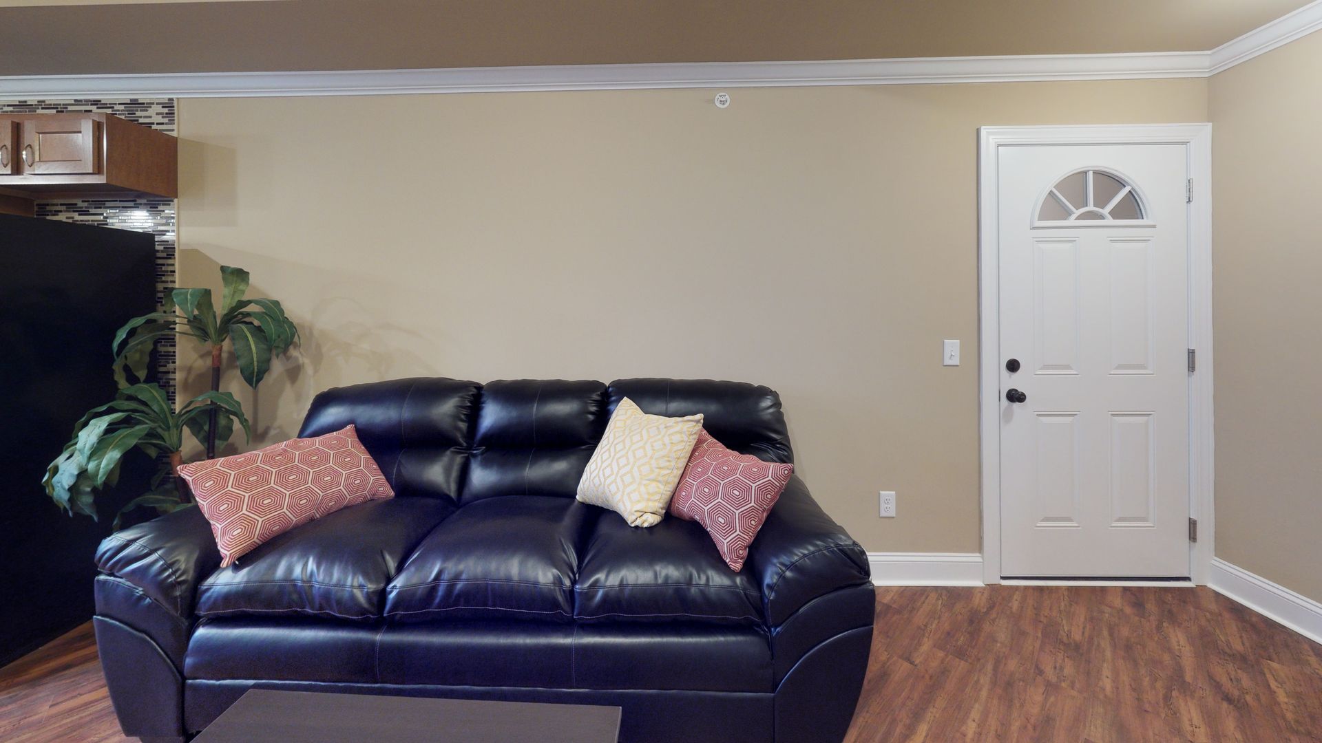 A living room with a black couch and a white door