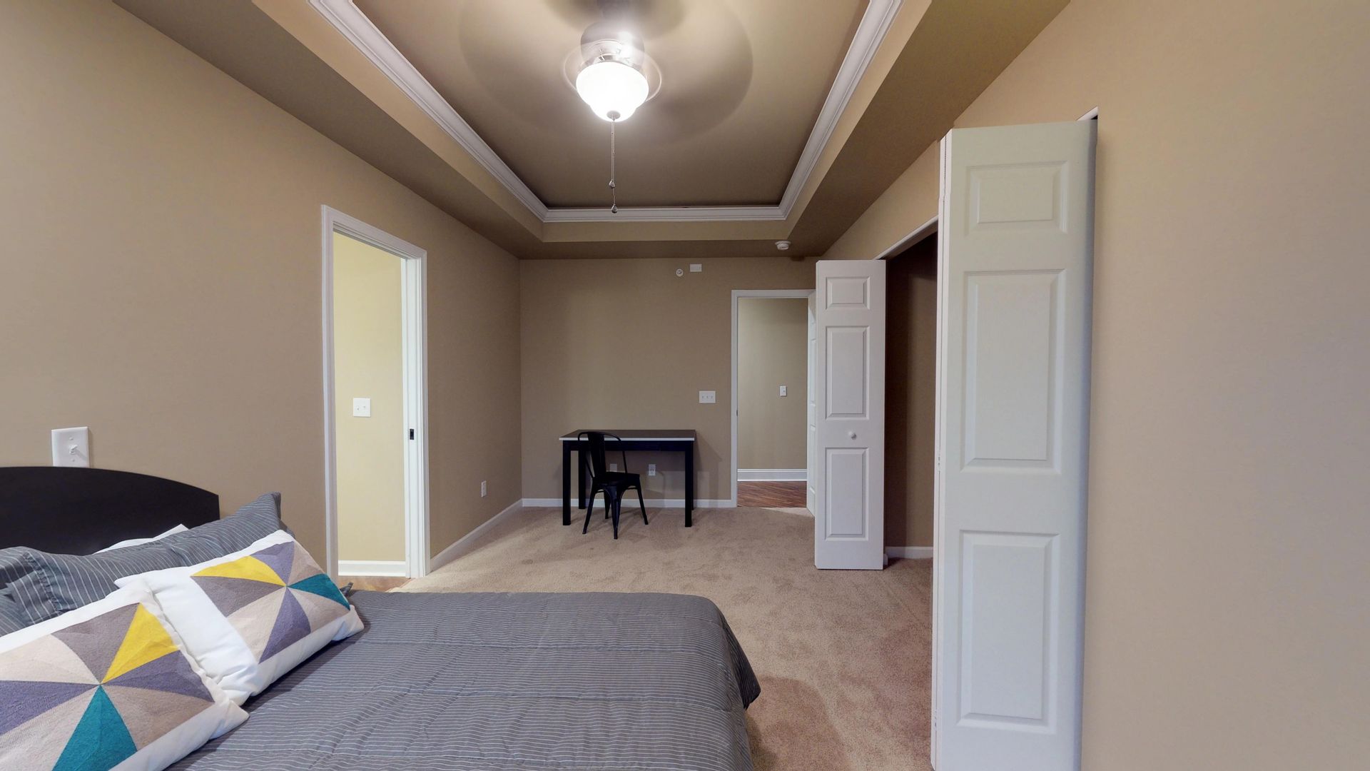 A bedroom with a bed , desk , and ceiling fan.