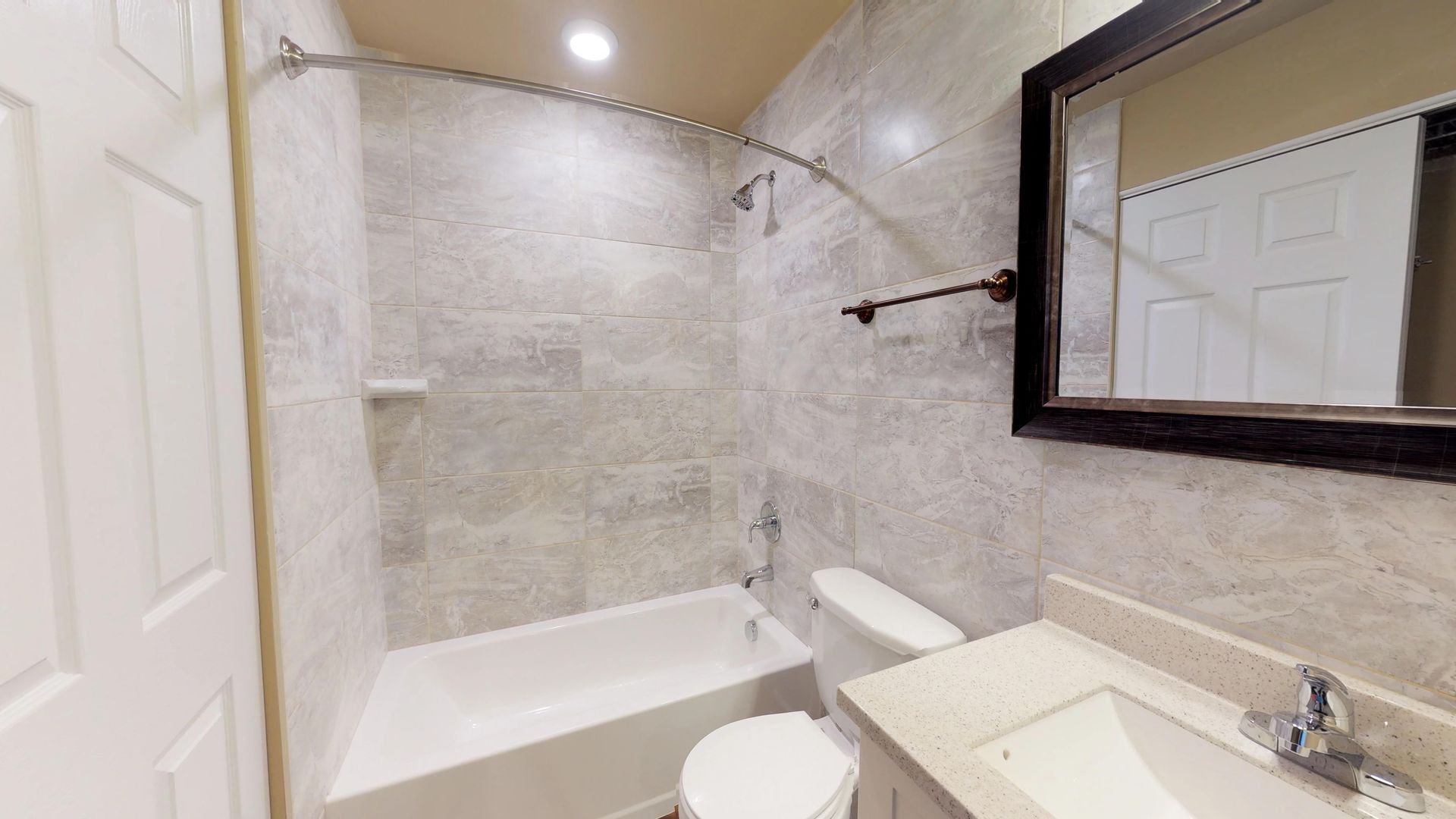 A bathroom with a toilet , sink , bathtub and mirror.
