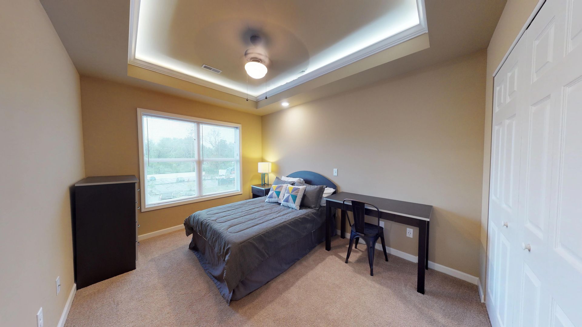 A bedroom with a bed , desk , and ceiling fan.