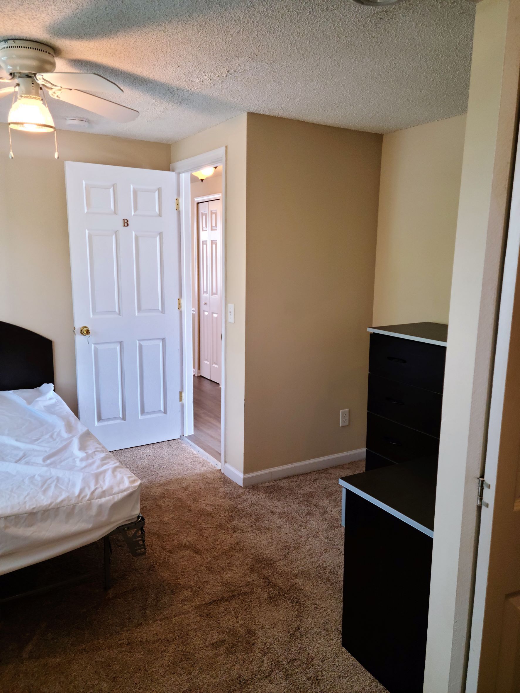 A bedroom with a bed and a ceiling fan.