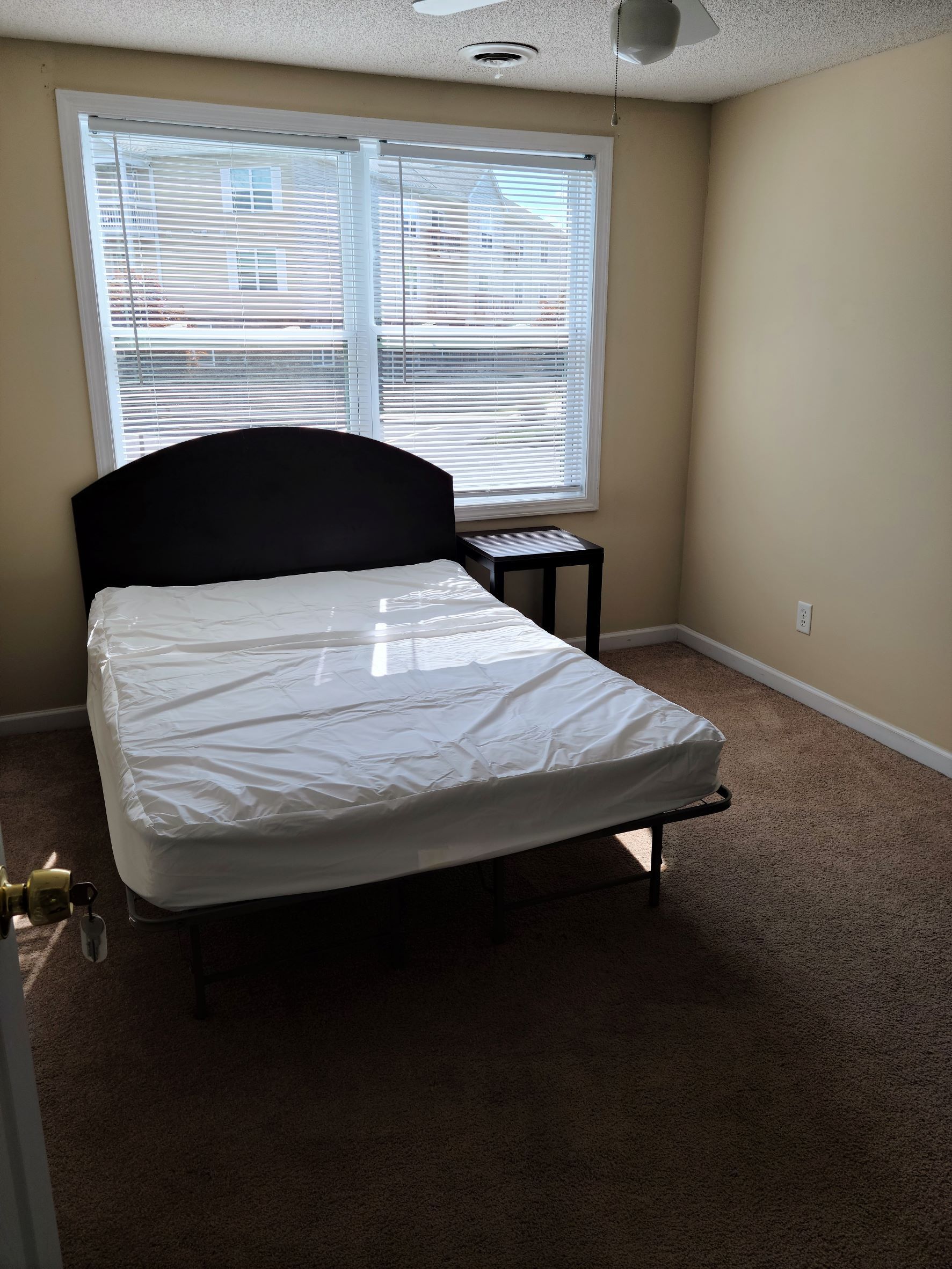 A bedroom with a bed and a window with blinds.