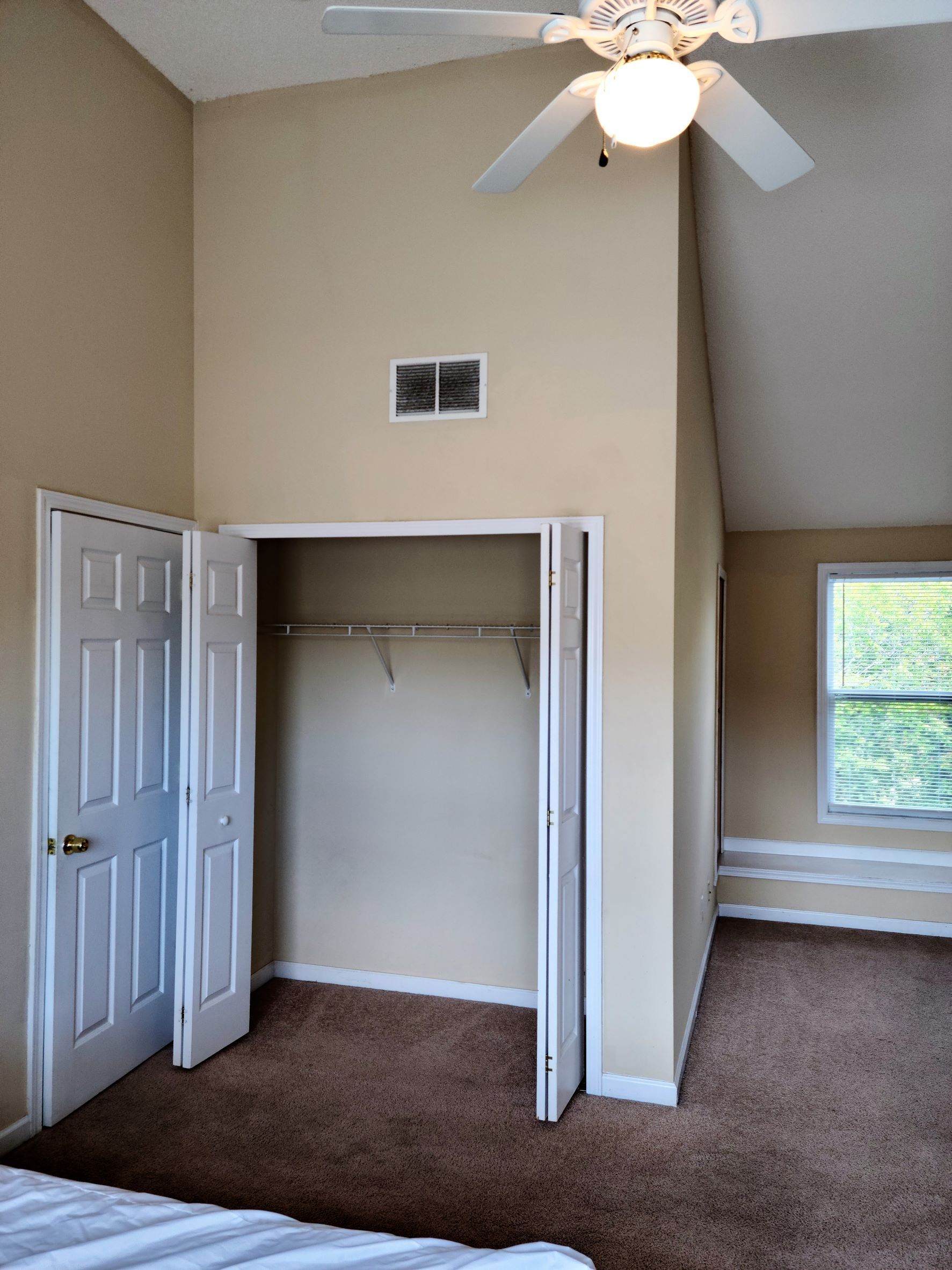 A bedroom with a ceiling fan and a closet