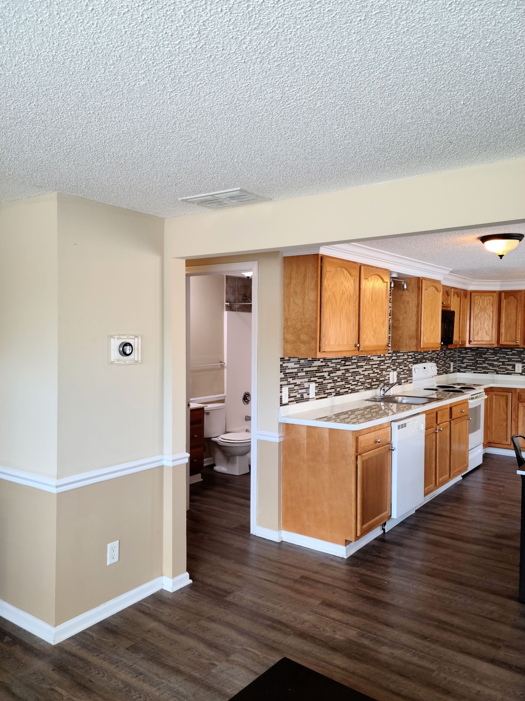 A kitchen with wooden cabinets , a sink , and a toilet.