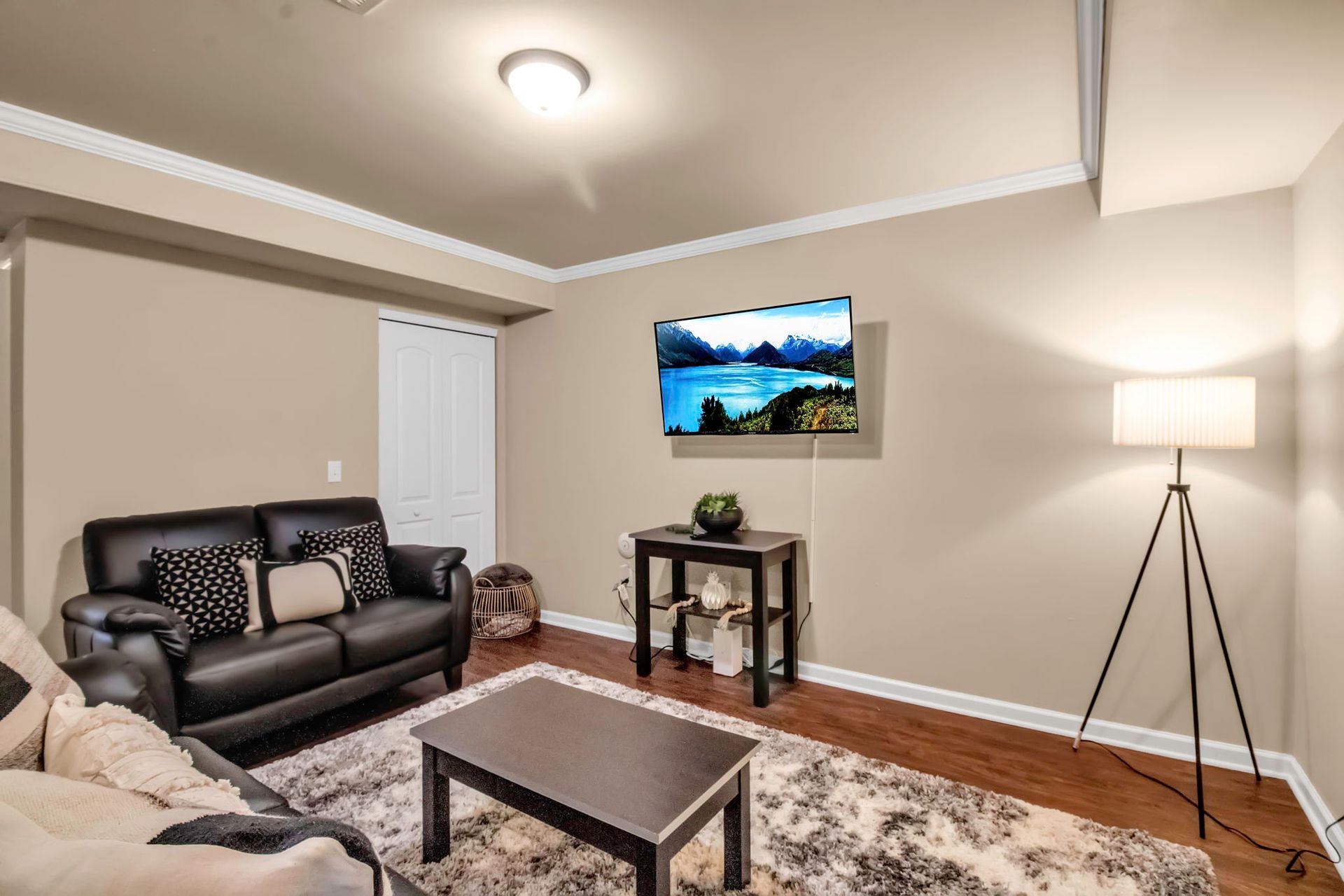 A living room with a couch , coffee table , lamp and television on the wall.