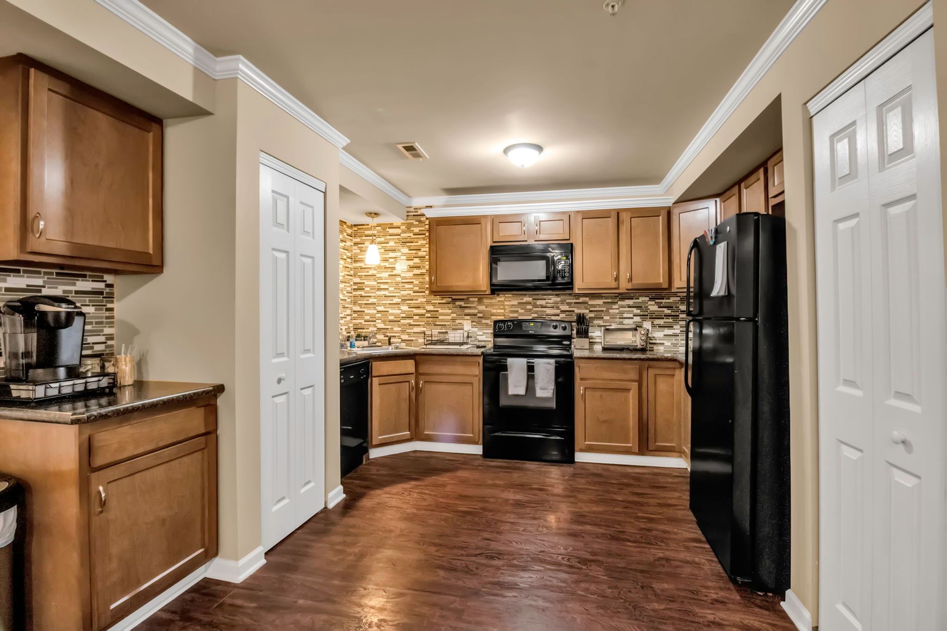 A kitchen with wooden cabinets , a black refrigerator , a stove , and a microwave.
