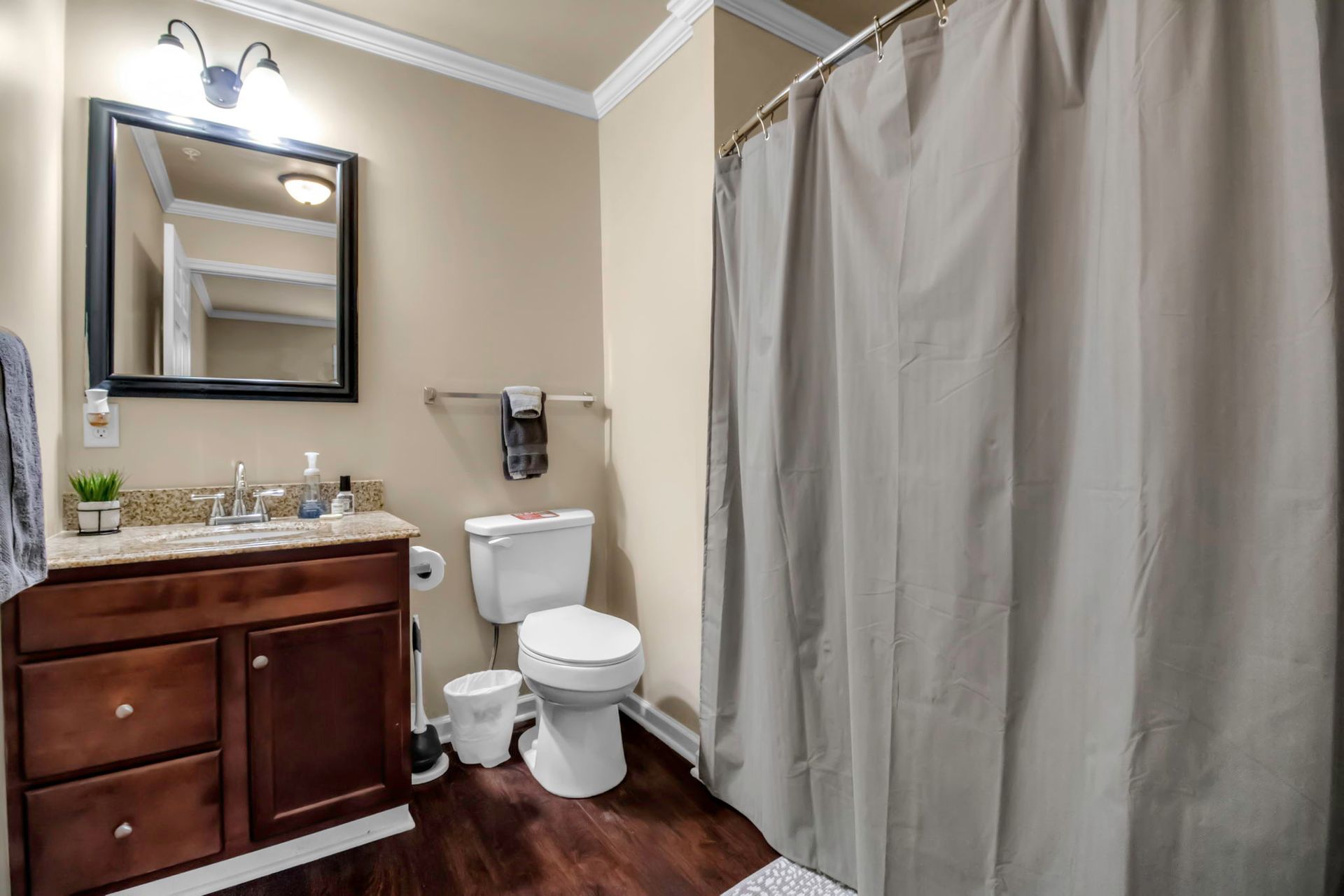 A bathroom with a toilet , sink , mirror and shower curtain.