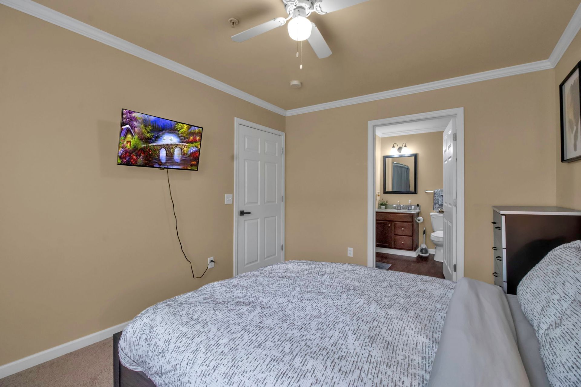 A bedroom with a bed a television and a ceiling fan