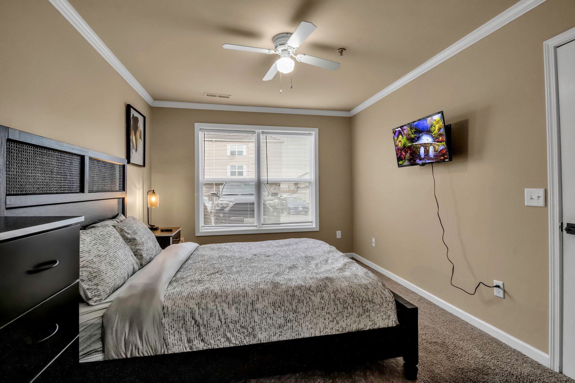 A bedroom with a bed and a television on the wall.