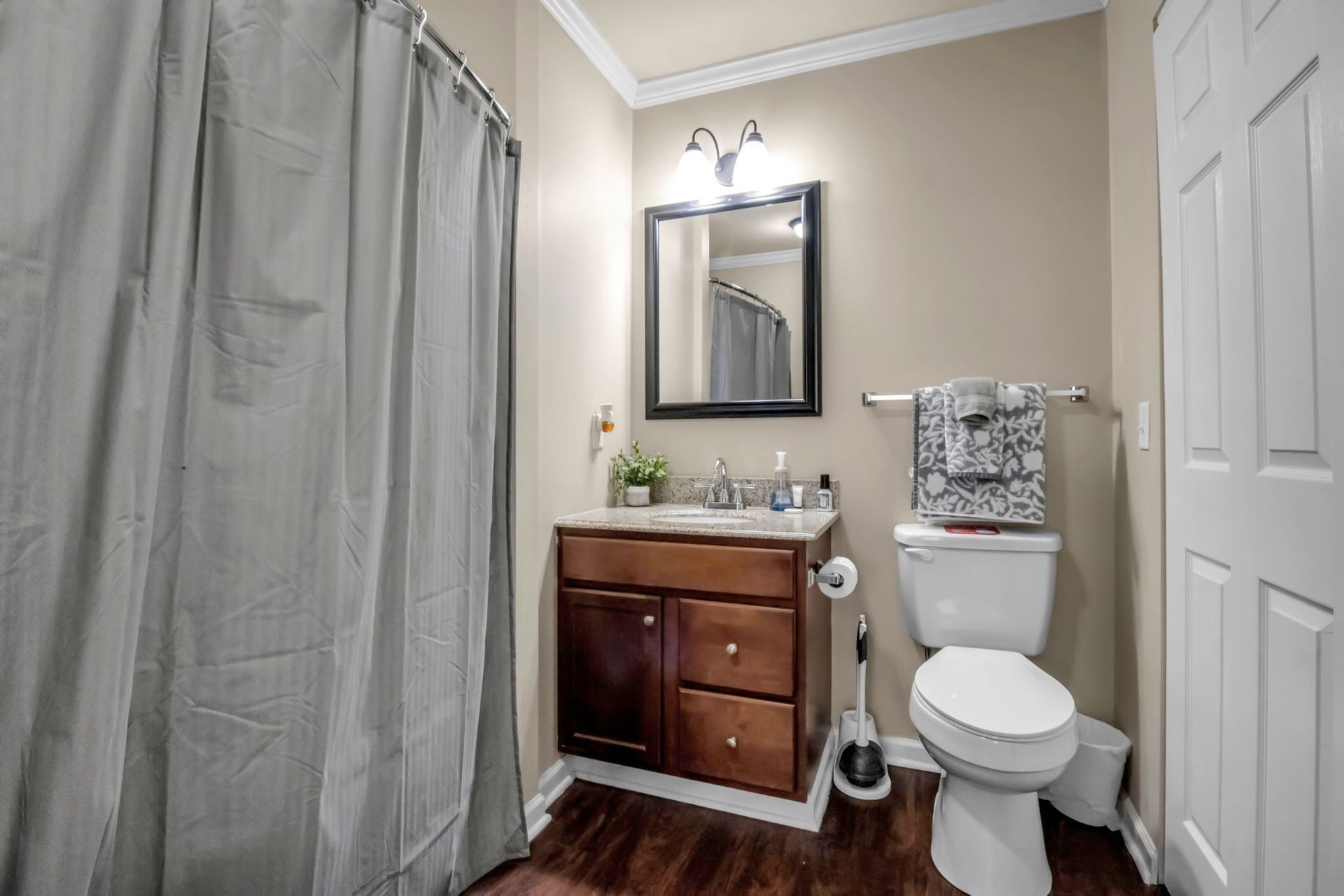 A bathroom with a toilet , sink , mirror and shower curtain.