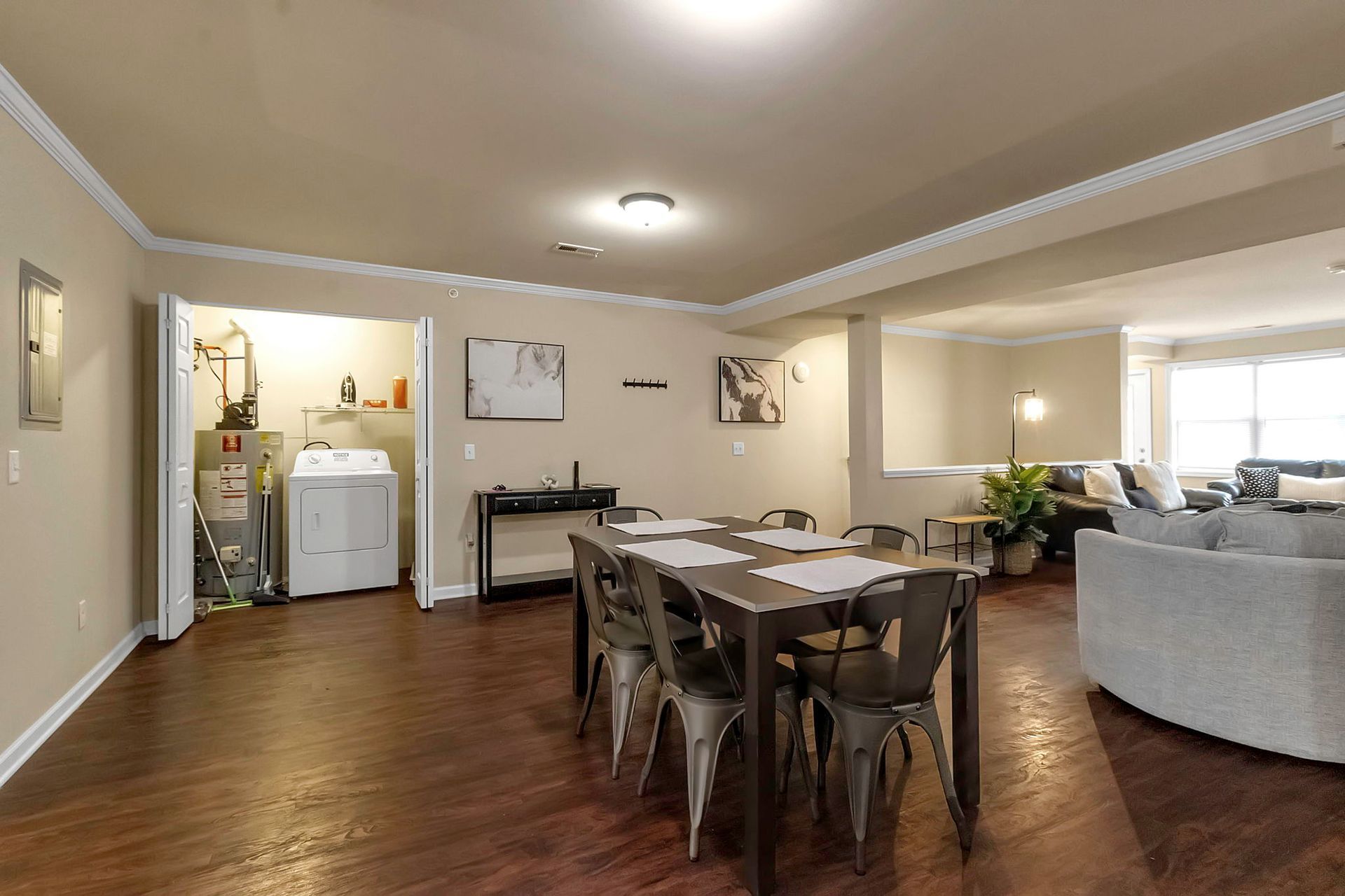 A living room with a dining table and chairs and a laundry room.