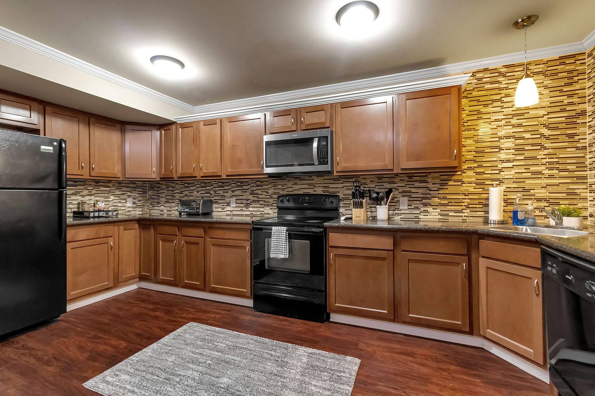 A kitchen with wooden cabinets and a black refrigerator