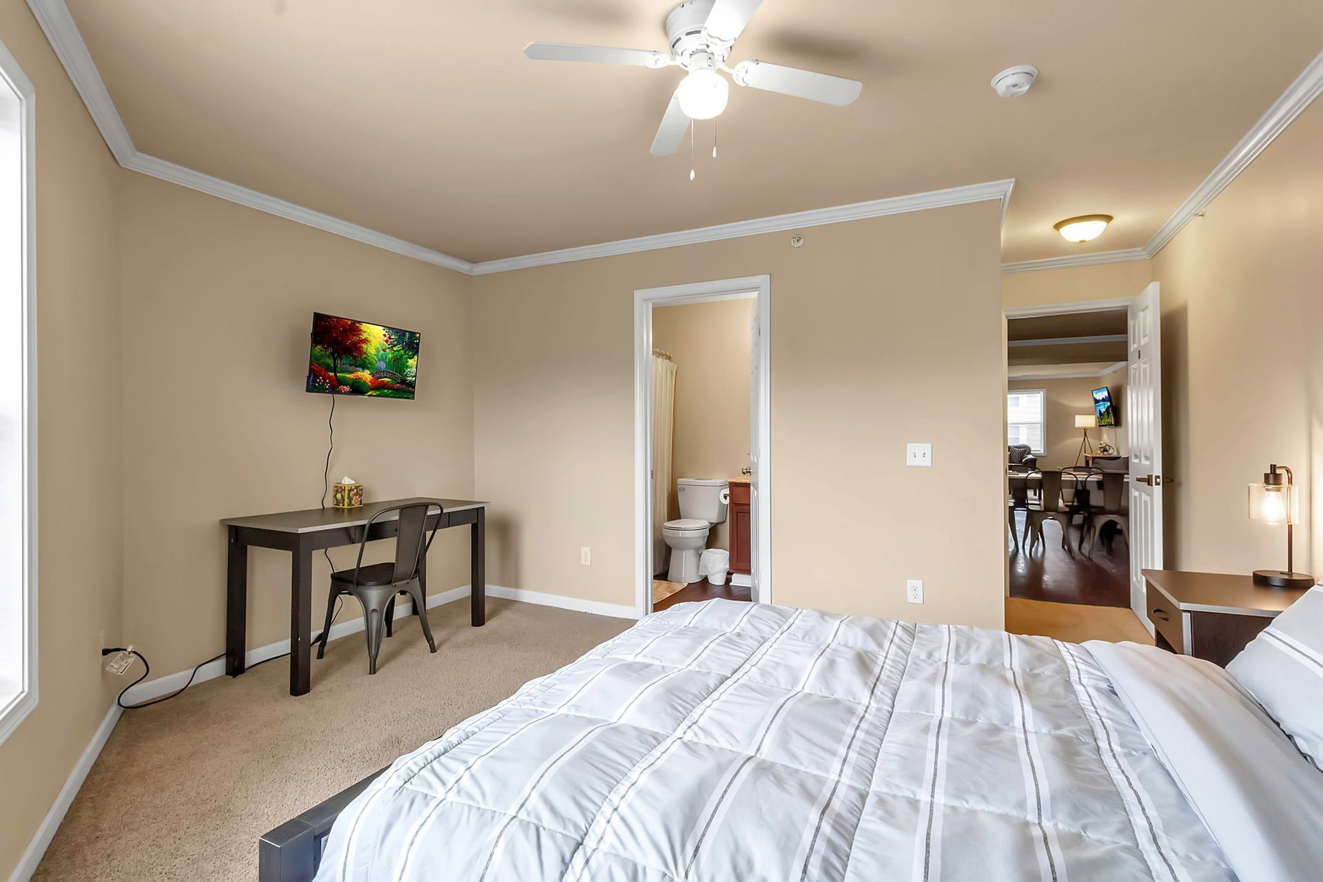 A bedroom with a bed , desk , chair and ceiling fan.