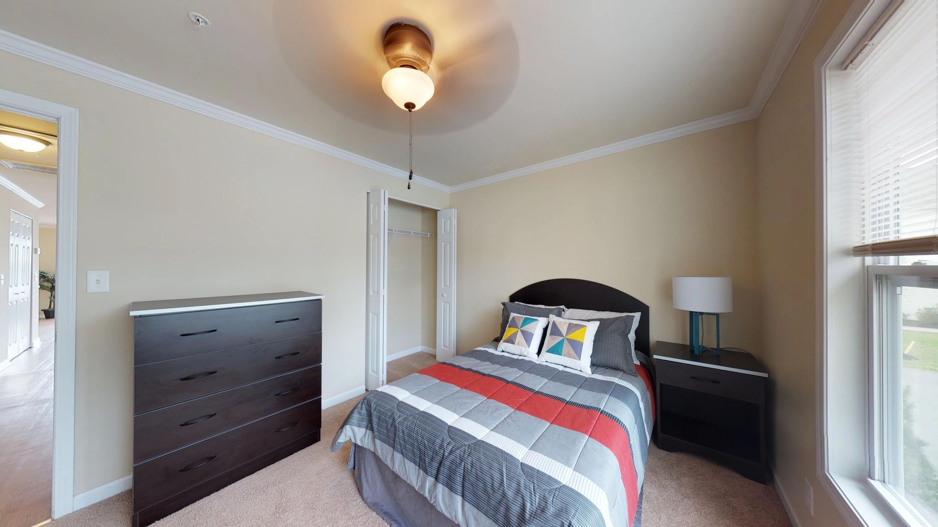 A bedroom with a bed , dresser , nightstand and window.