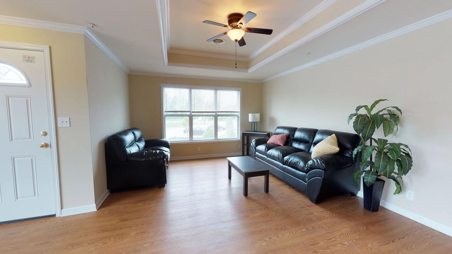 A living room with a black couch and a ceiling fan
