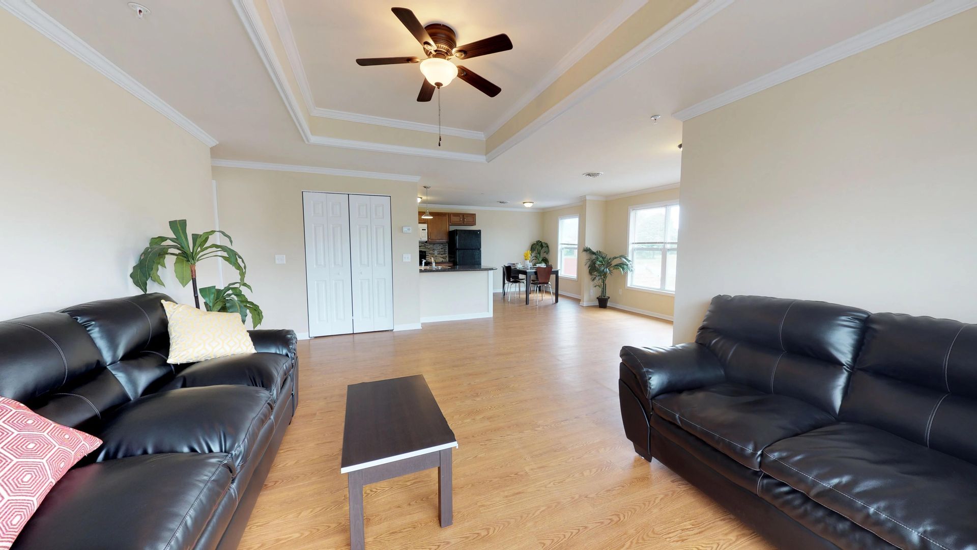 A living room with two couches , a coffee table and a ceiling fan.