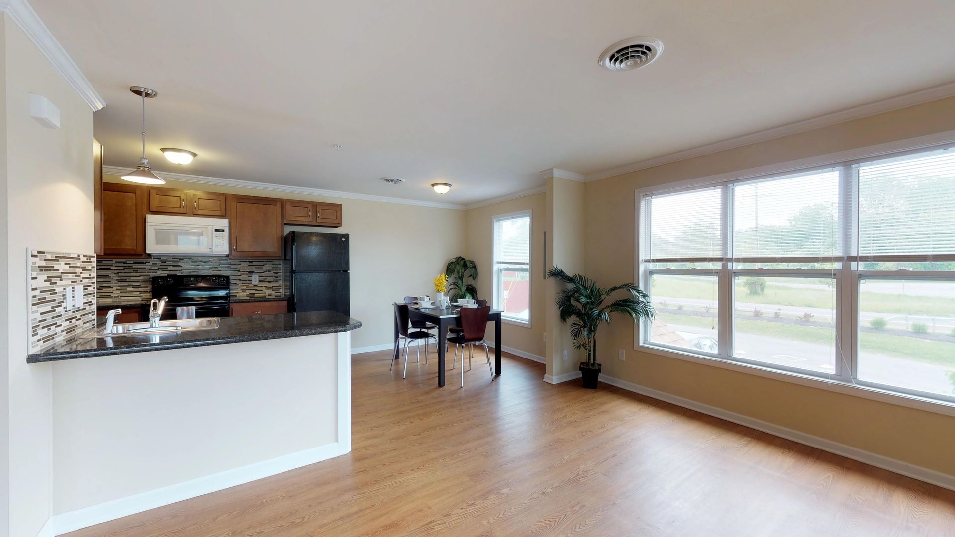 A living room with hardwood floors and a kitchen with a table and chairs.