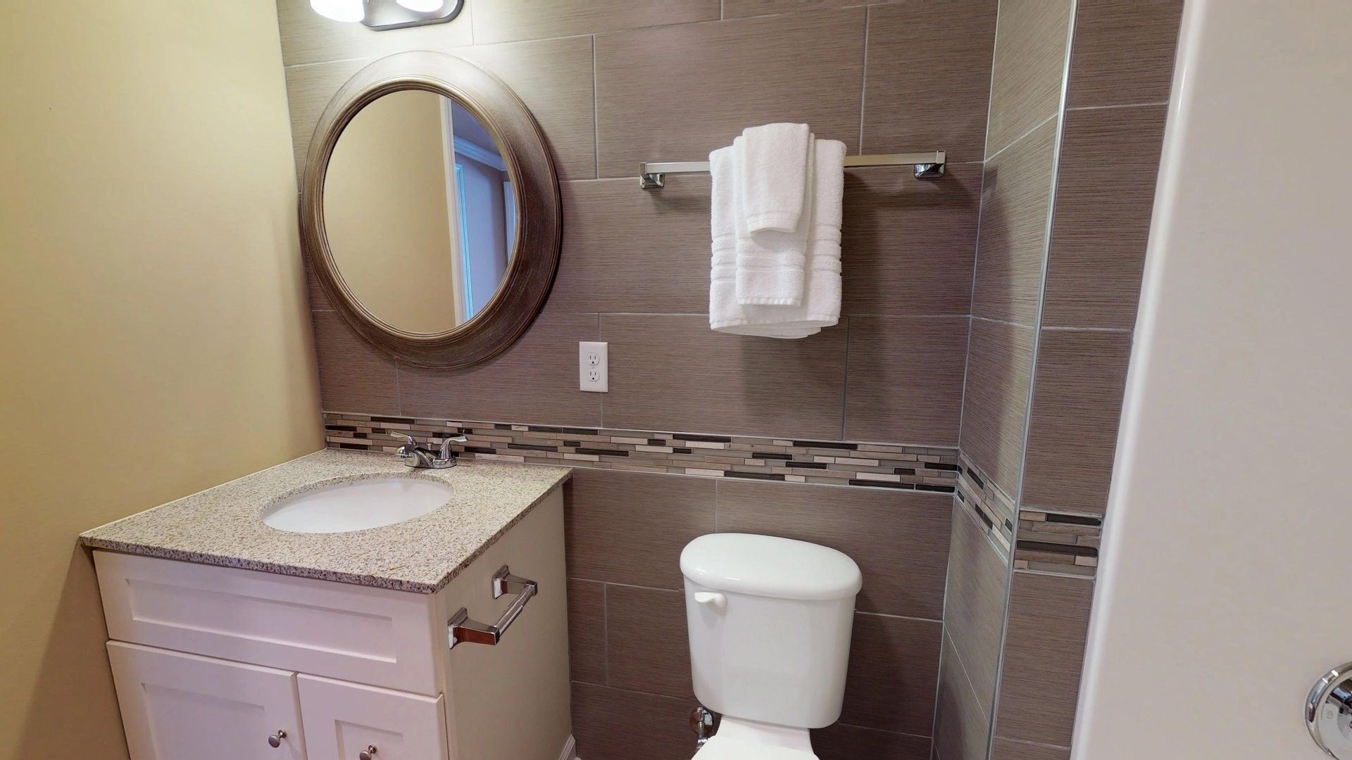 A bathroom with a toilet , sink and mirror.
