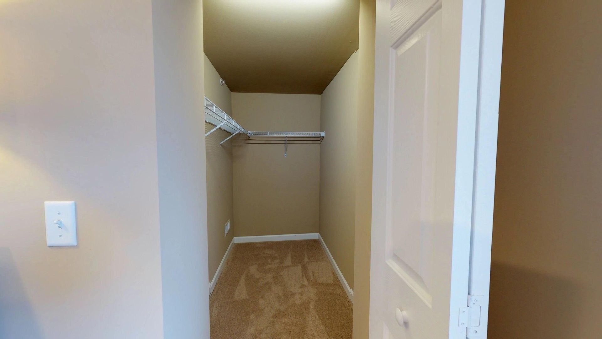 A walk in closet with wooden floors and a white door.