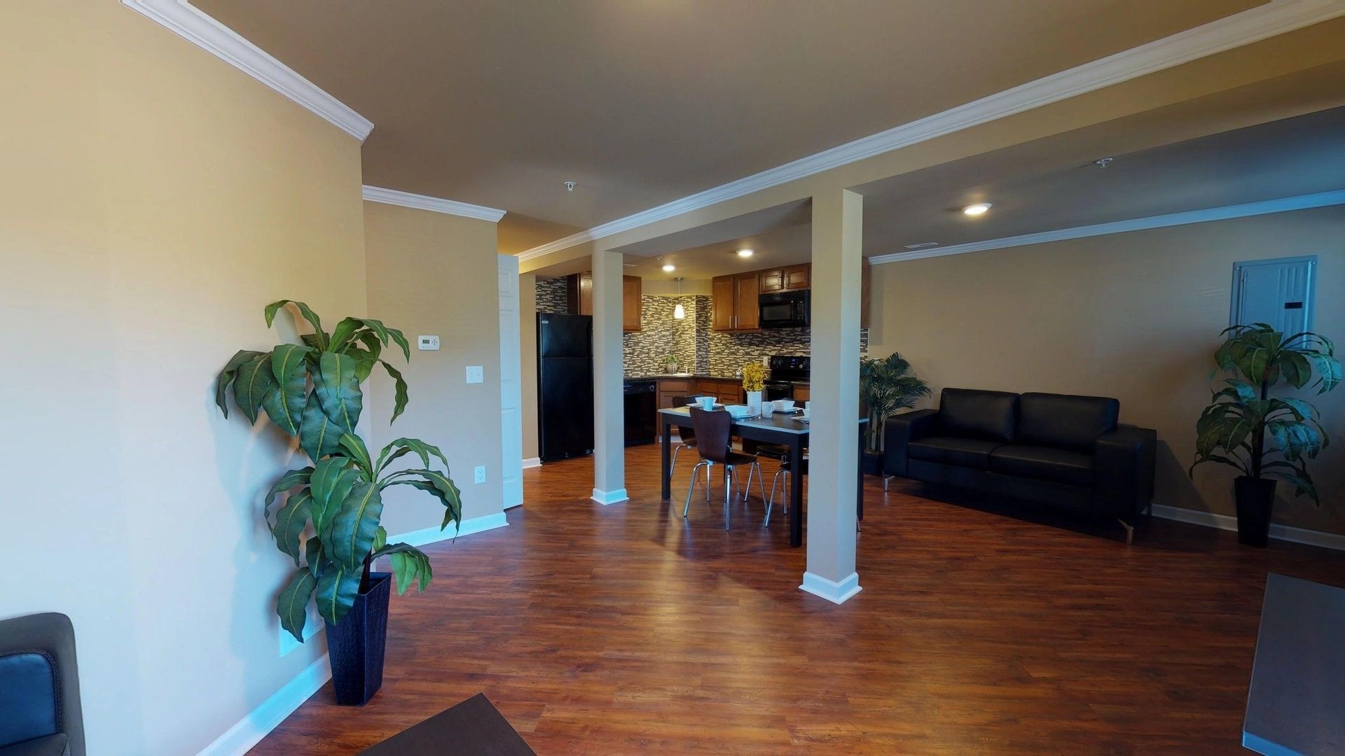 A living room with hardwood floors , a couch , a table and a potted plant.