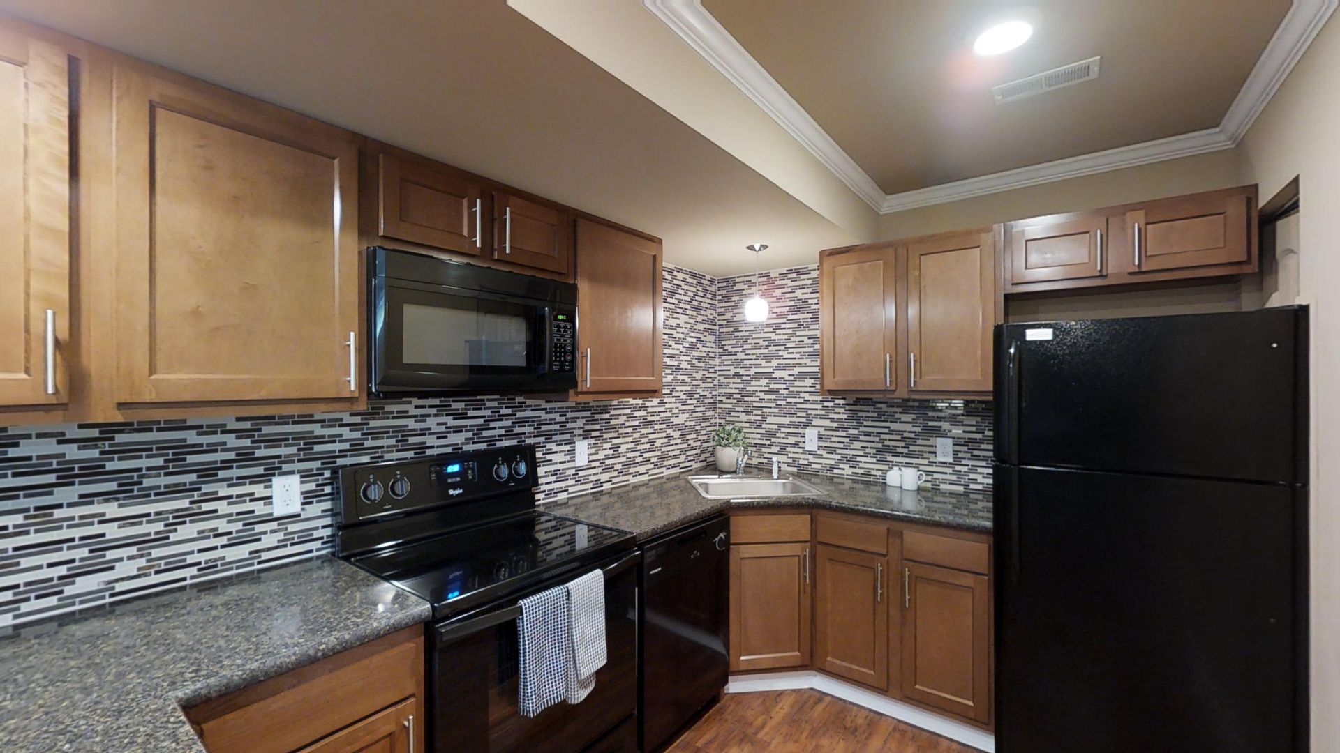 A kitchen with a black refrigerator , stove , microwave and sink.