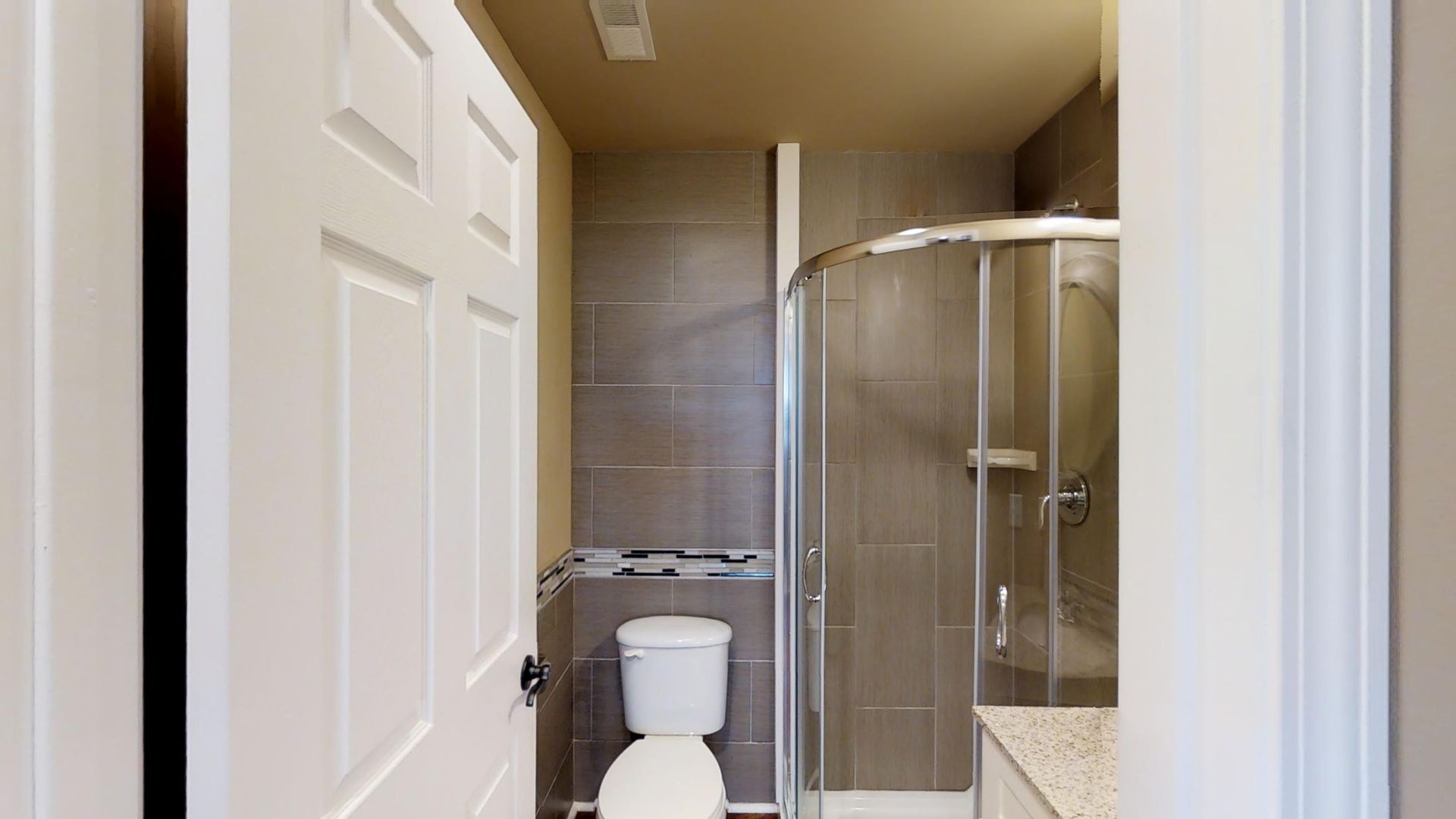 A bathroom with a toilet and a walk in shower.