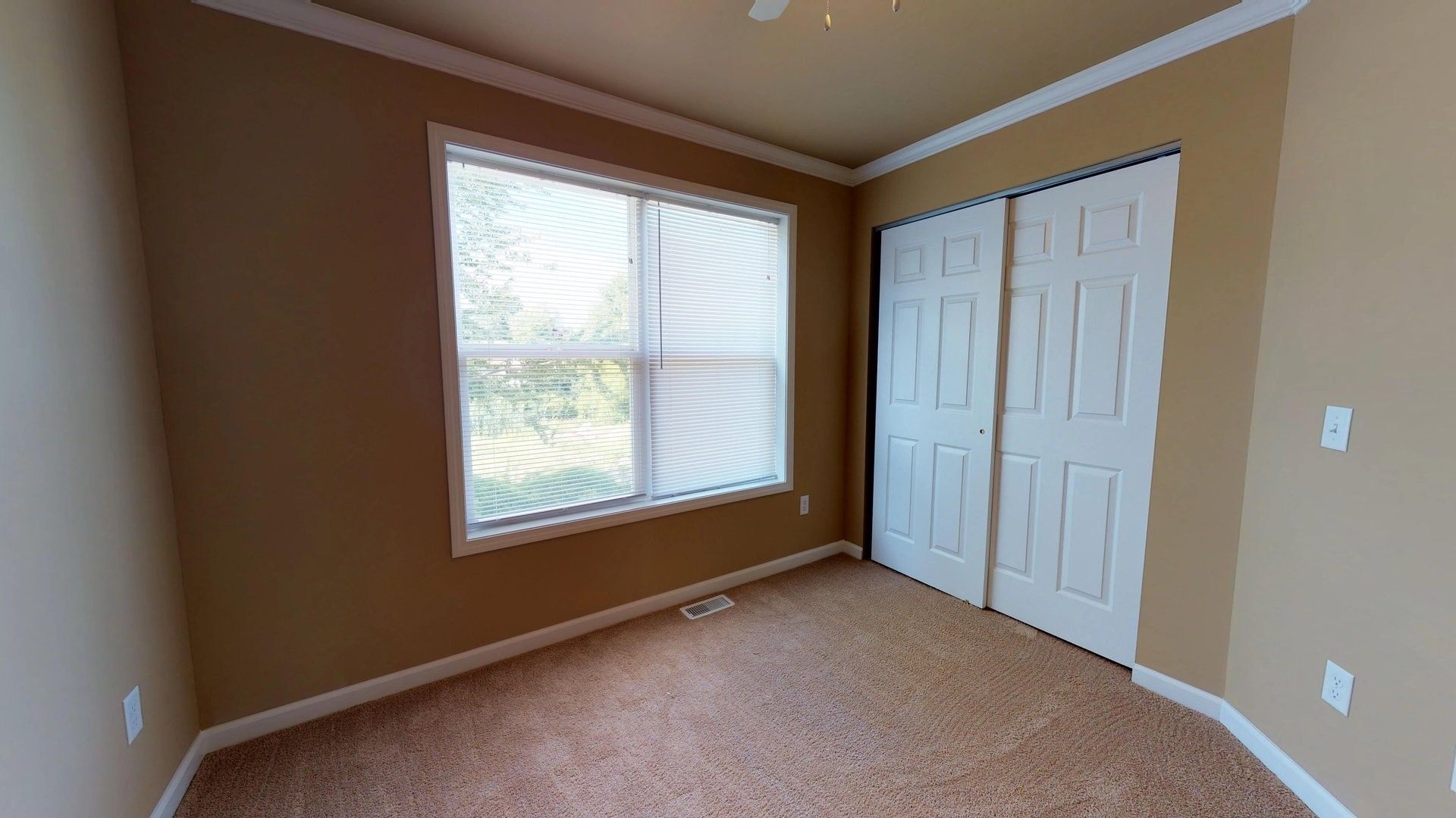 An empty bedroom with two windows and sliding doors.
