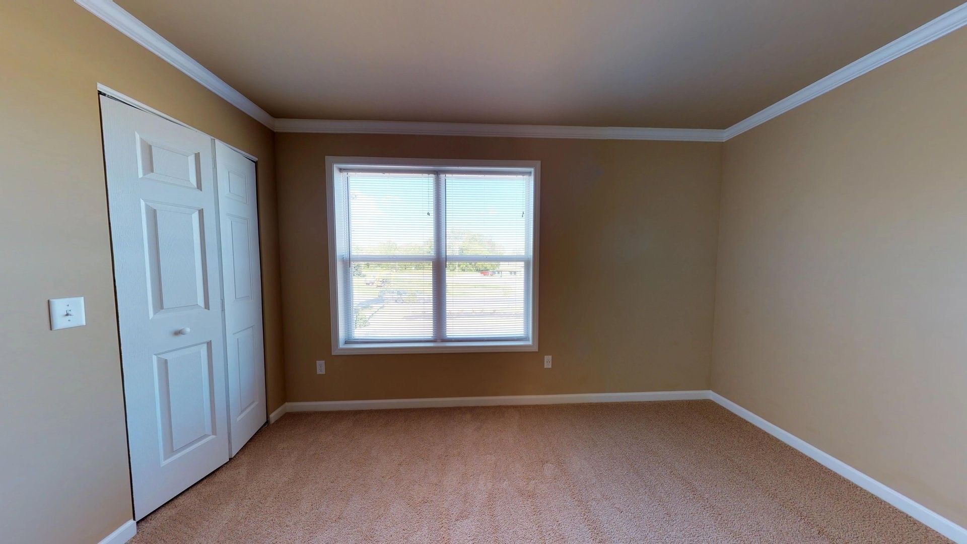 An empty room with a window and a closet.