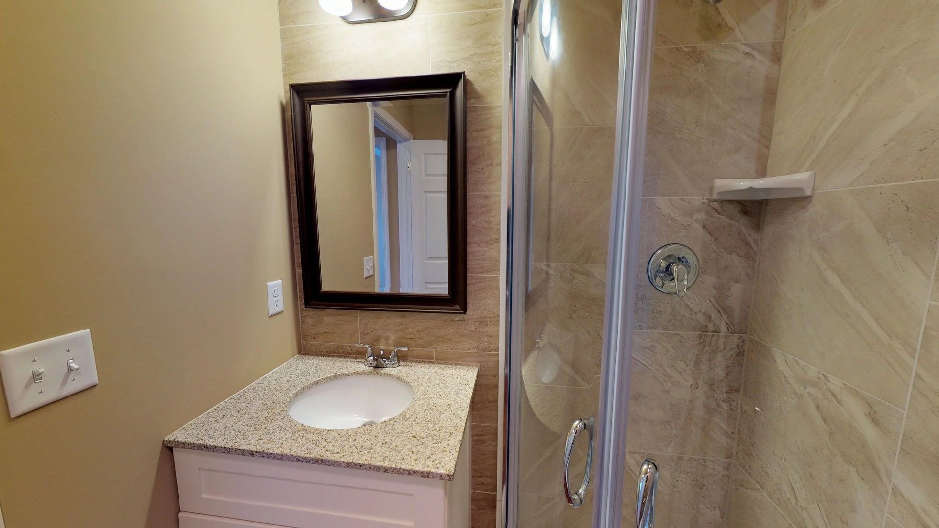 A bathroom with a sink , mirror and shower.