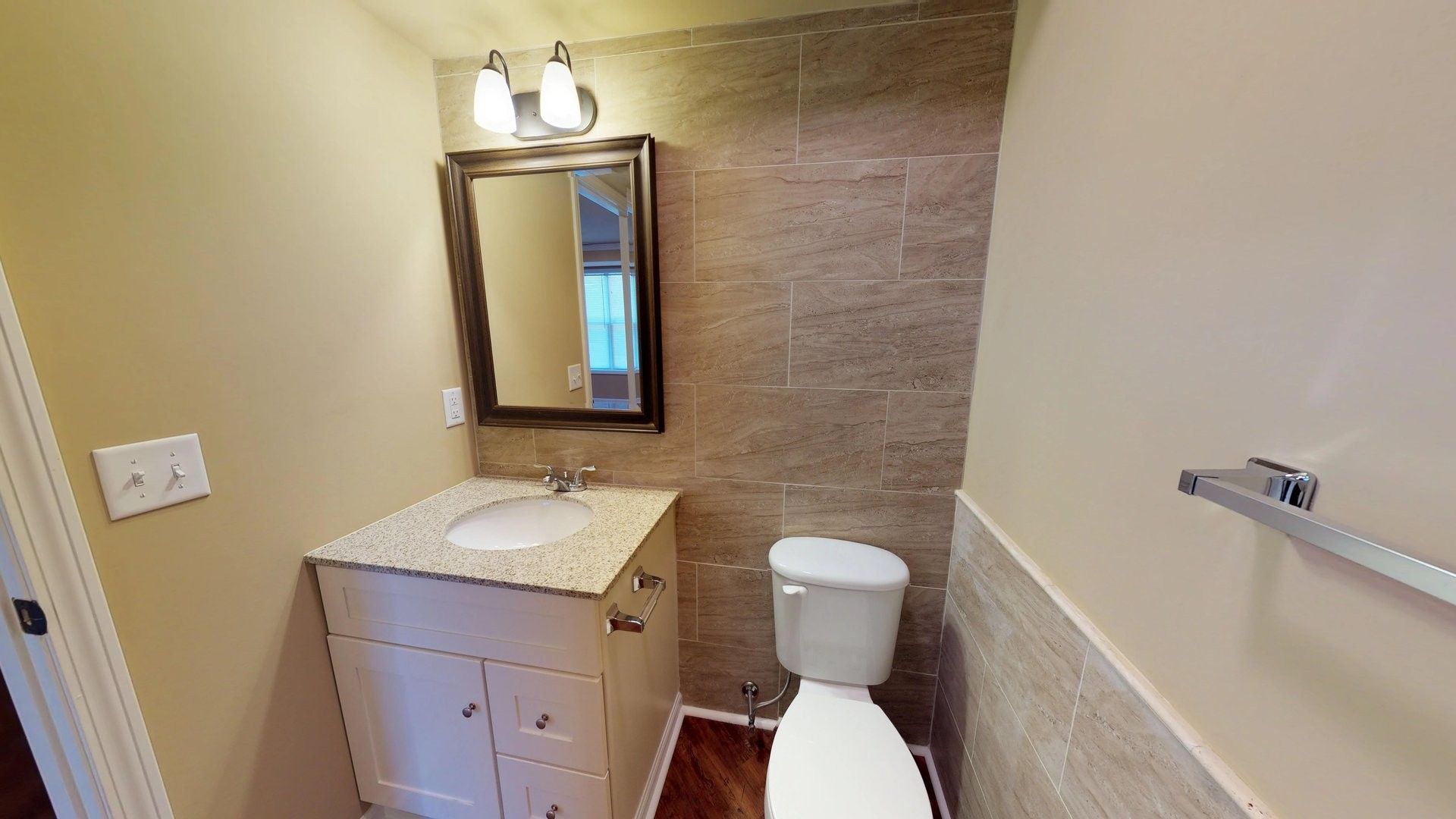 A bathroom with a toilet , sink and mirror.