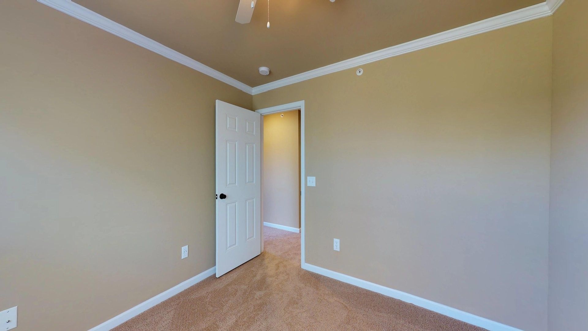 An empty bedroom with a ceiling fan and a door.