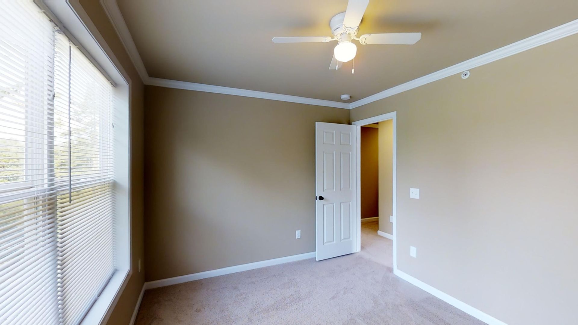 An empty bedroom with a ceiling fan and a window.