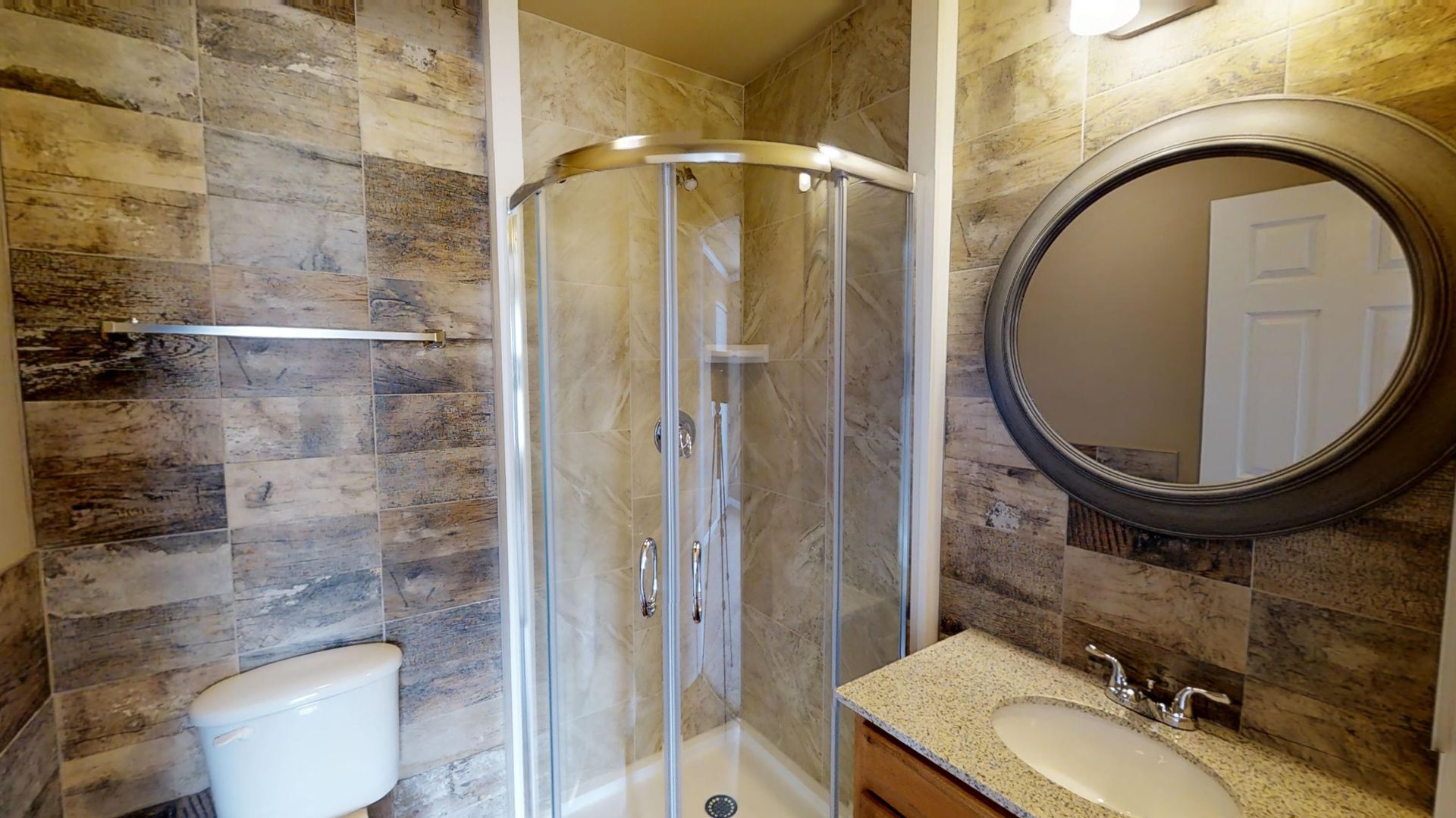 A bathroom with a toilet , sink , shower and mirror.